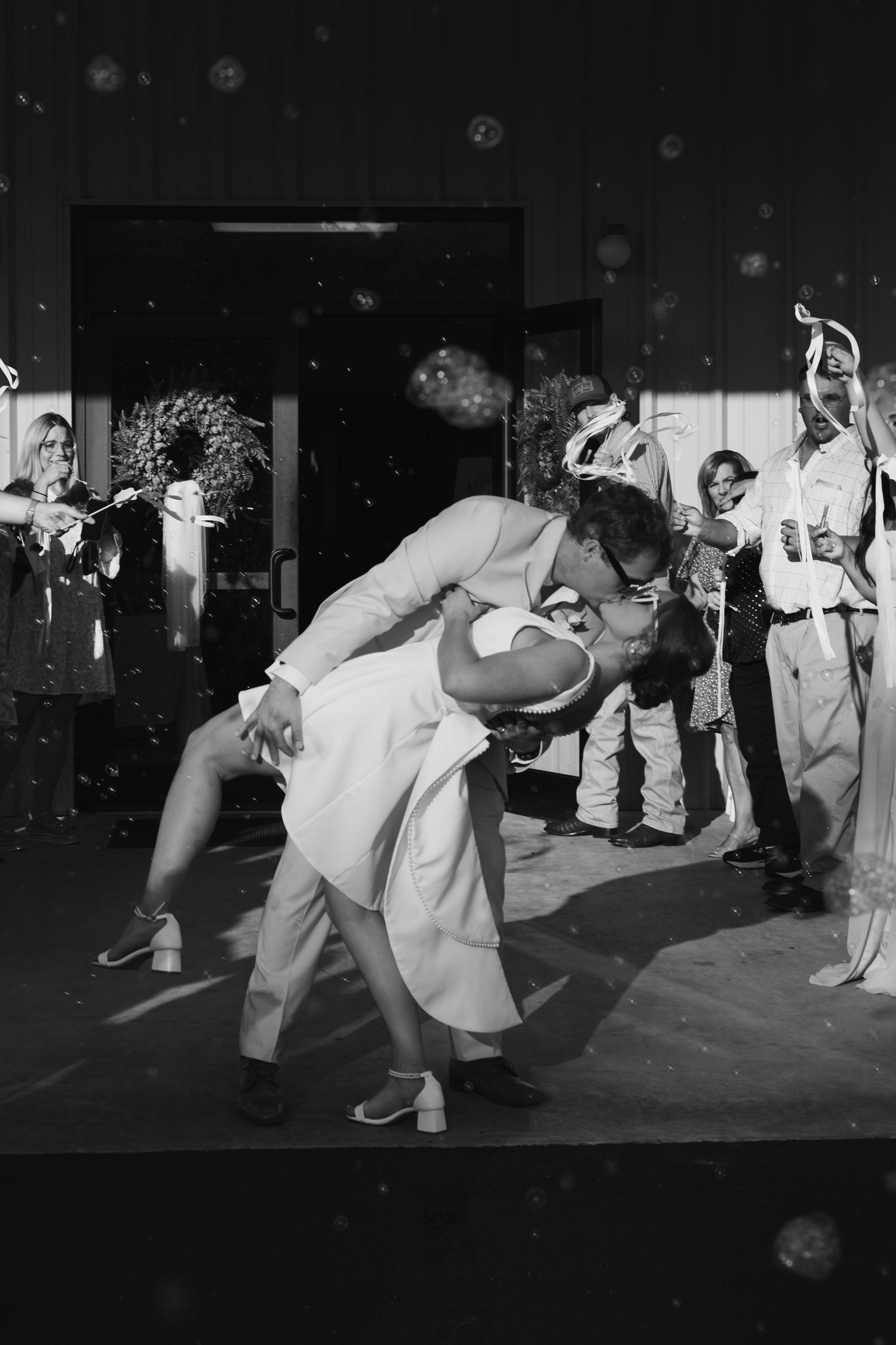 Black and white photo of groom dipping bride for a kiss on the dance floor.