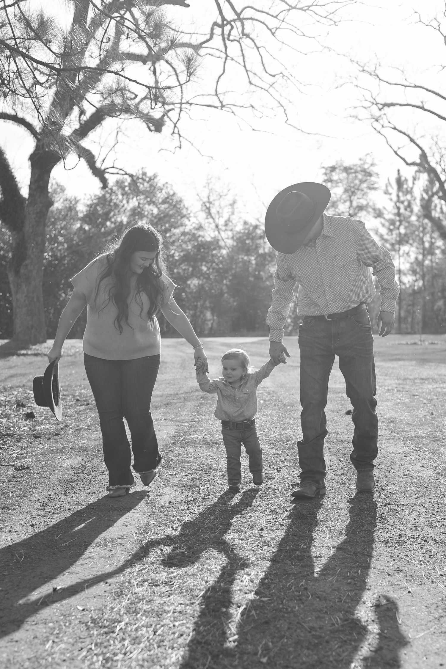 Black and white photo of shadows cast by people walking together in a park on a sunny day.