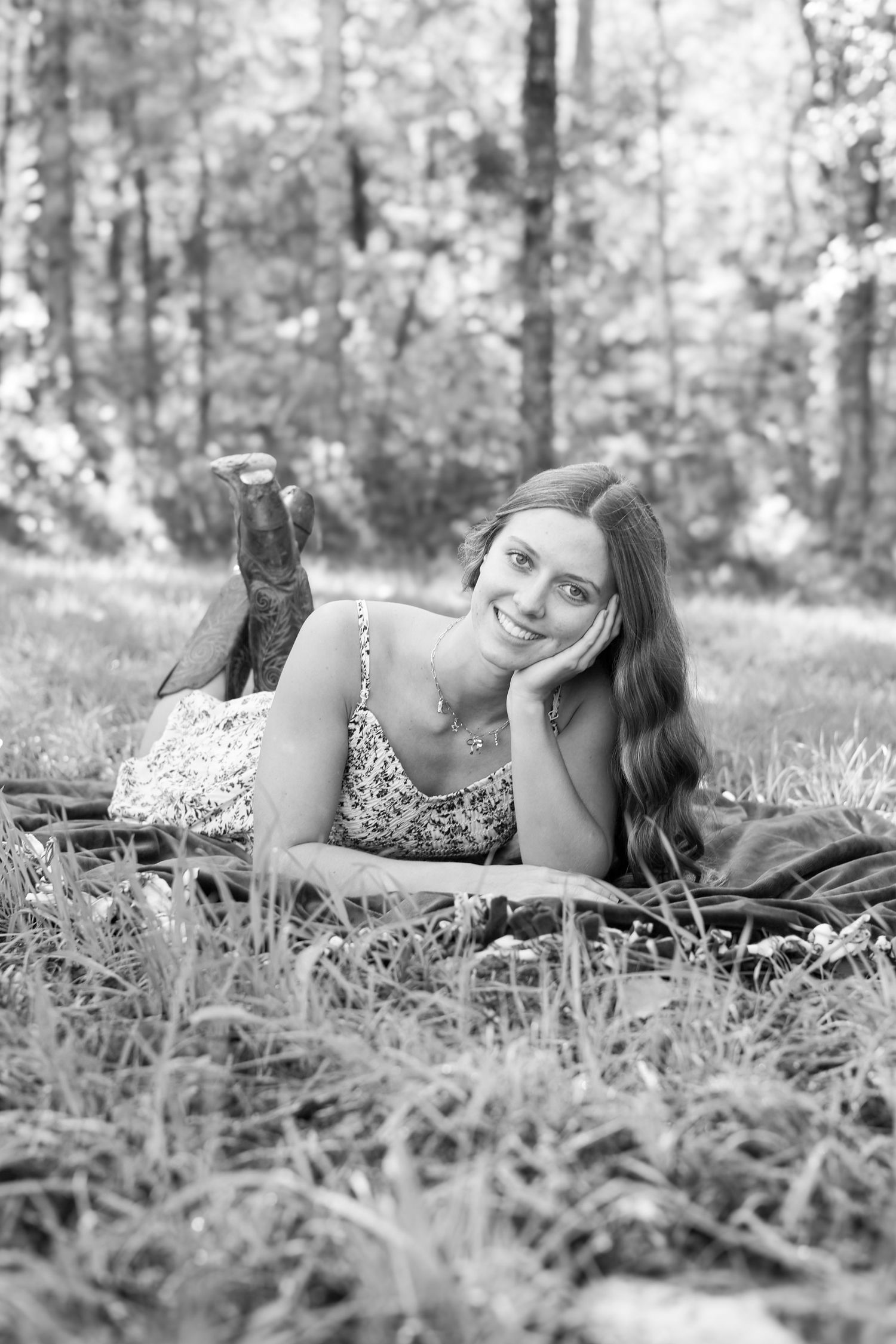 Black and white photo series of person lying in grass wearing floral dress.