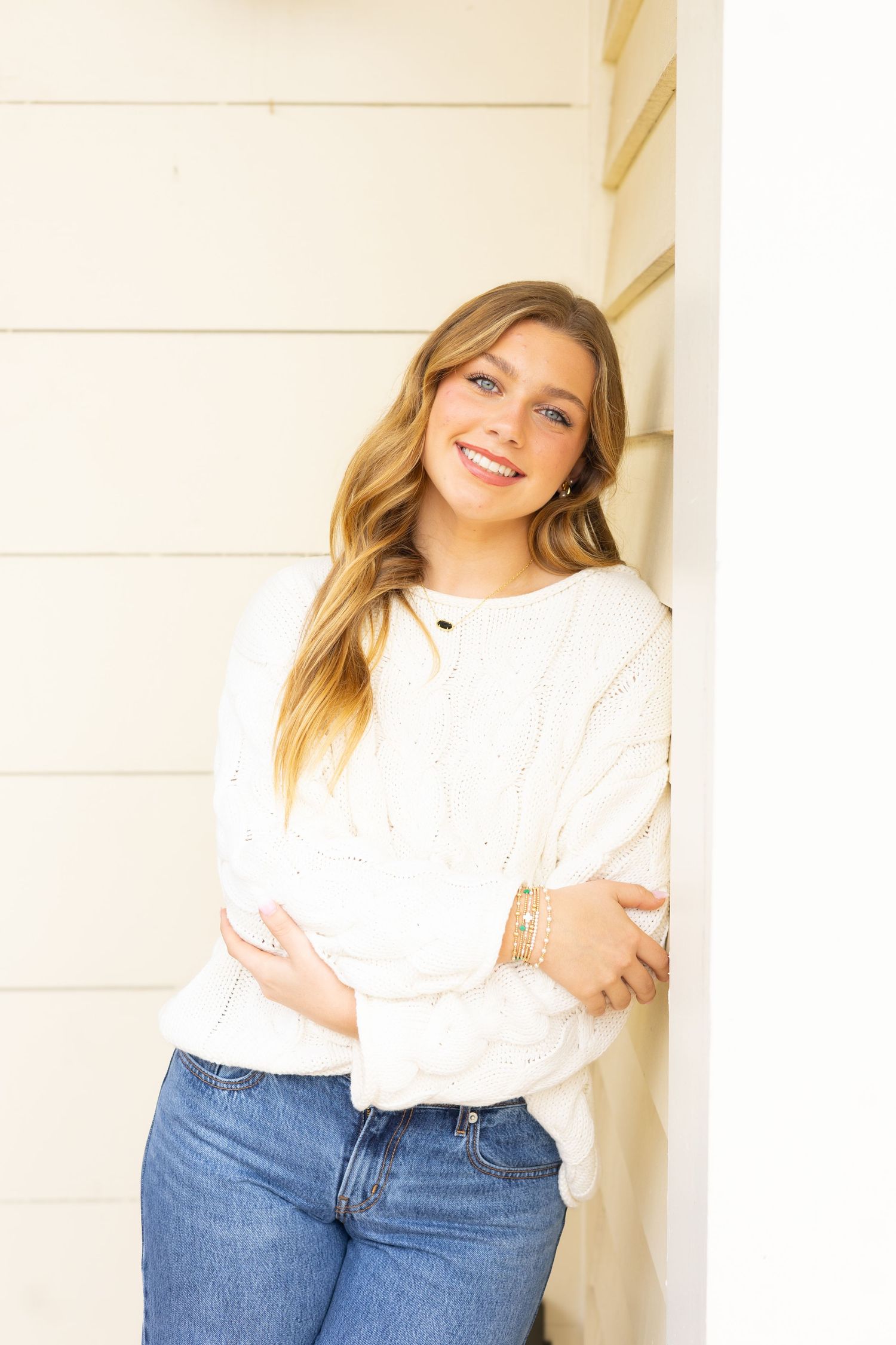 Casual lifestyle portrait against white wall wearing classic blue jeans and white top in natural light.