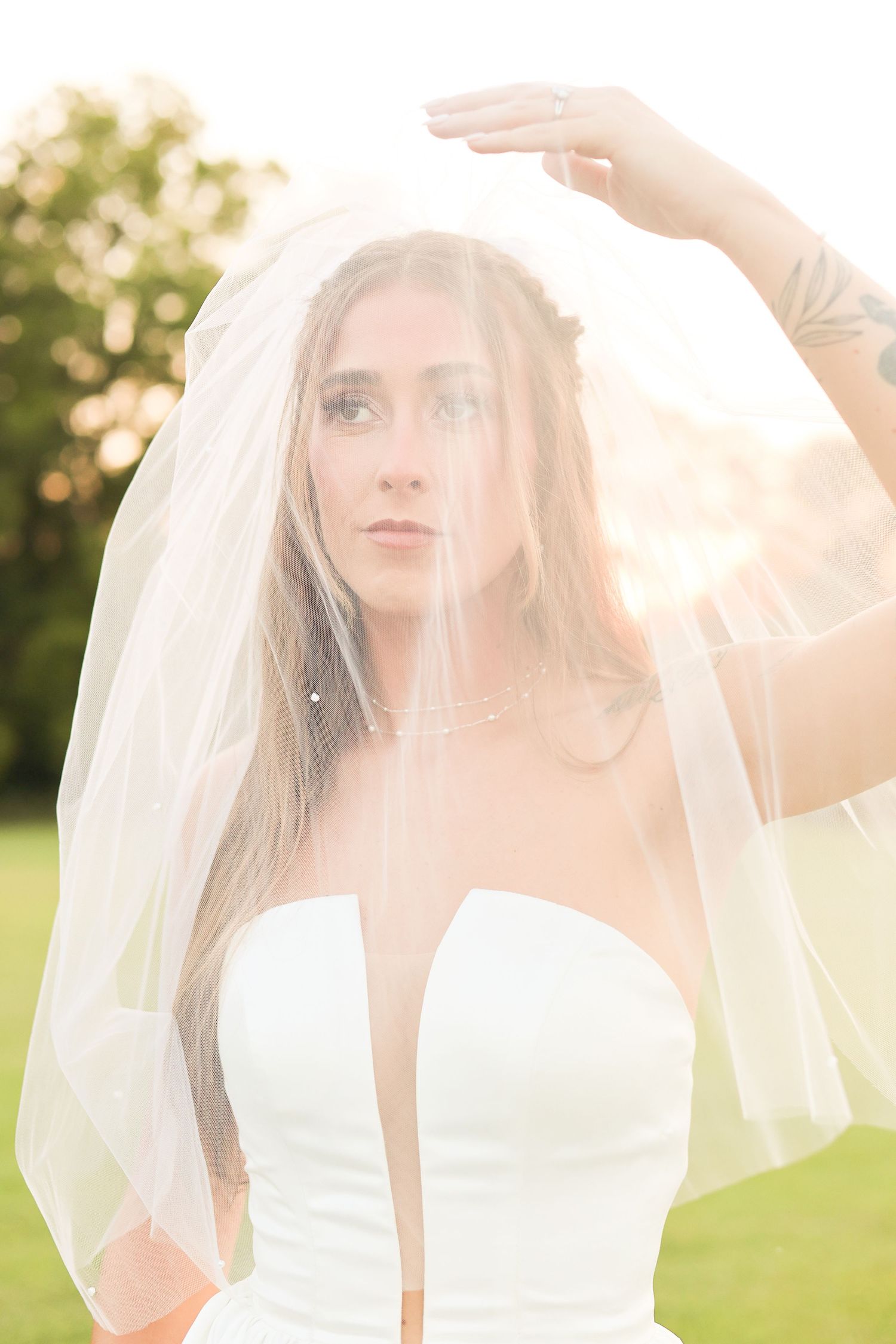 Ethereal bridal portrait with sunlit veil in outdoor garden setting.