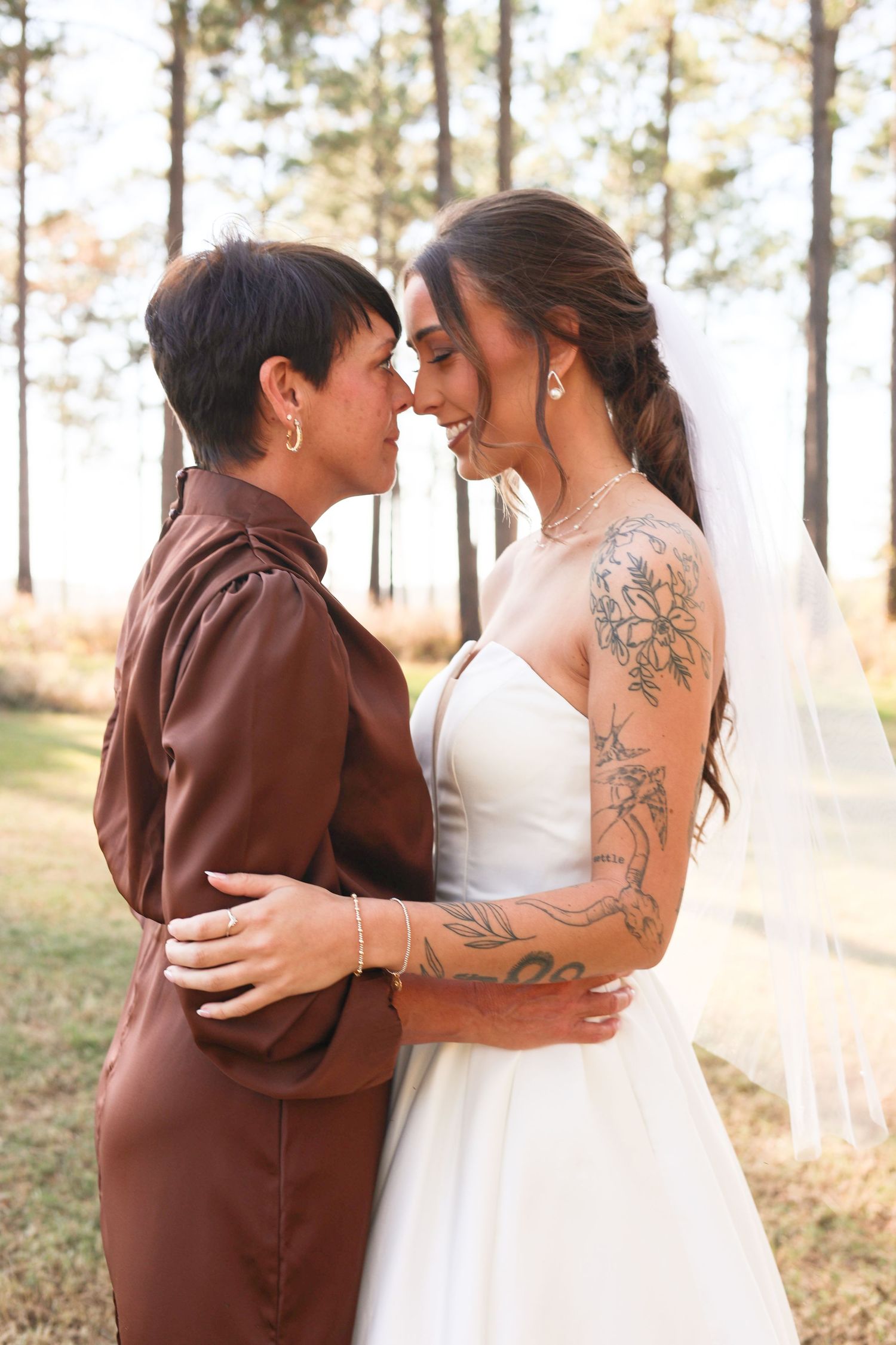 Emotional embrace between wedding couple in pine forest during sunset.