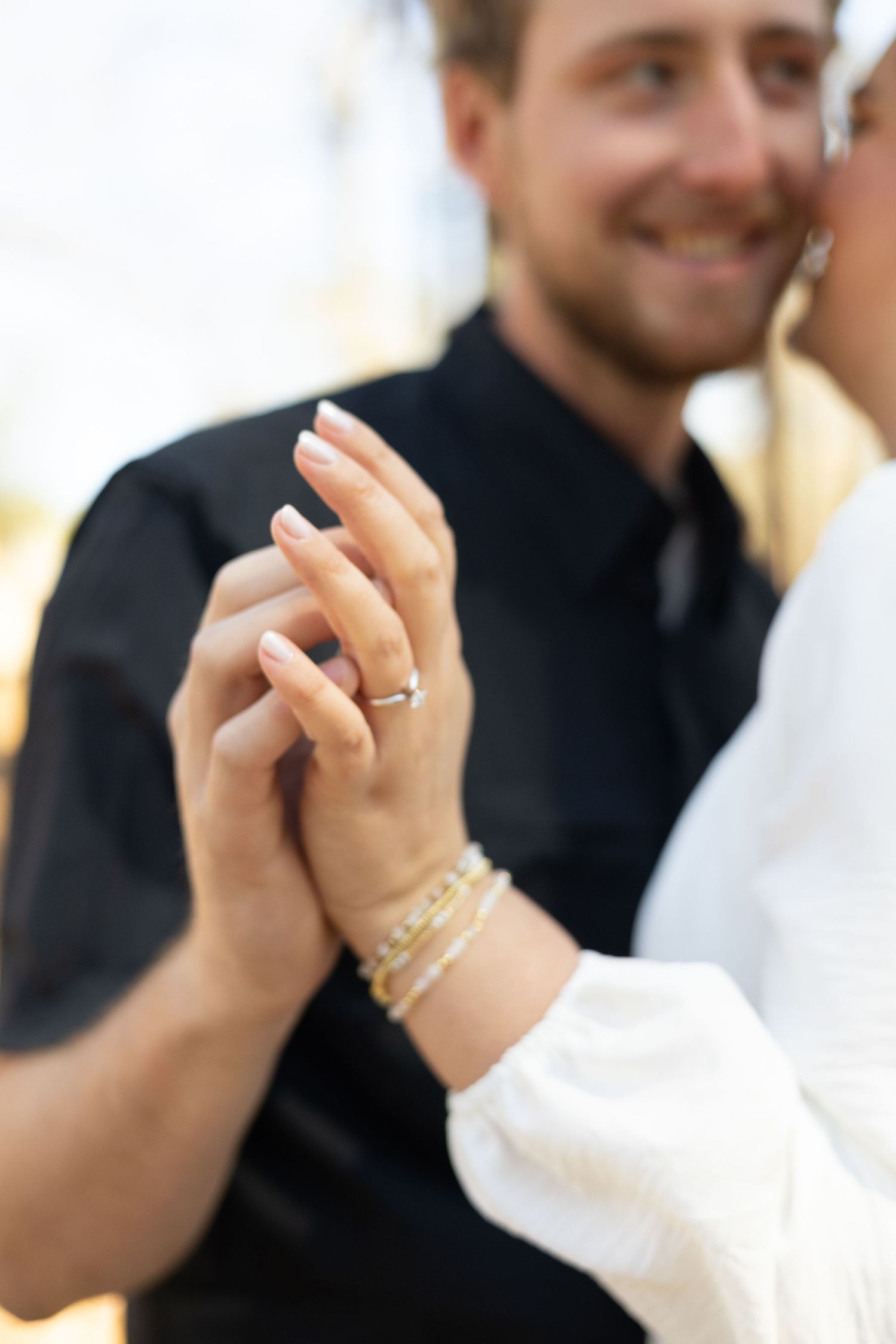 Close-up view of clasped hands dancing at a formal event with black and white attire.