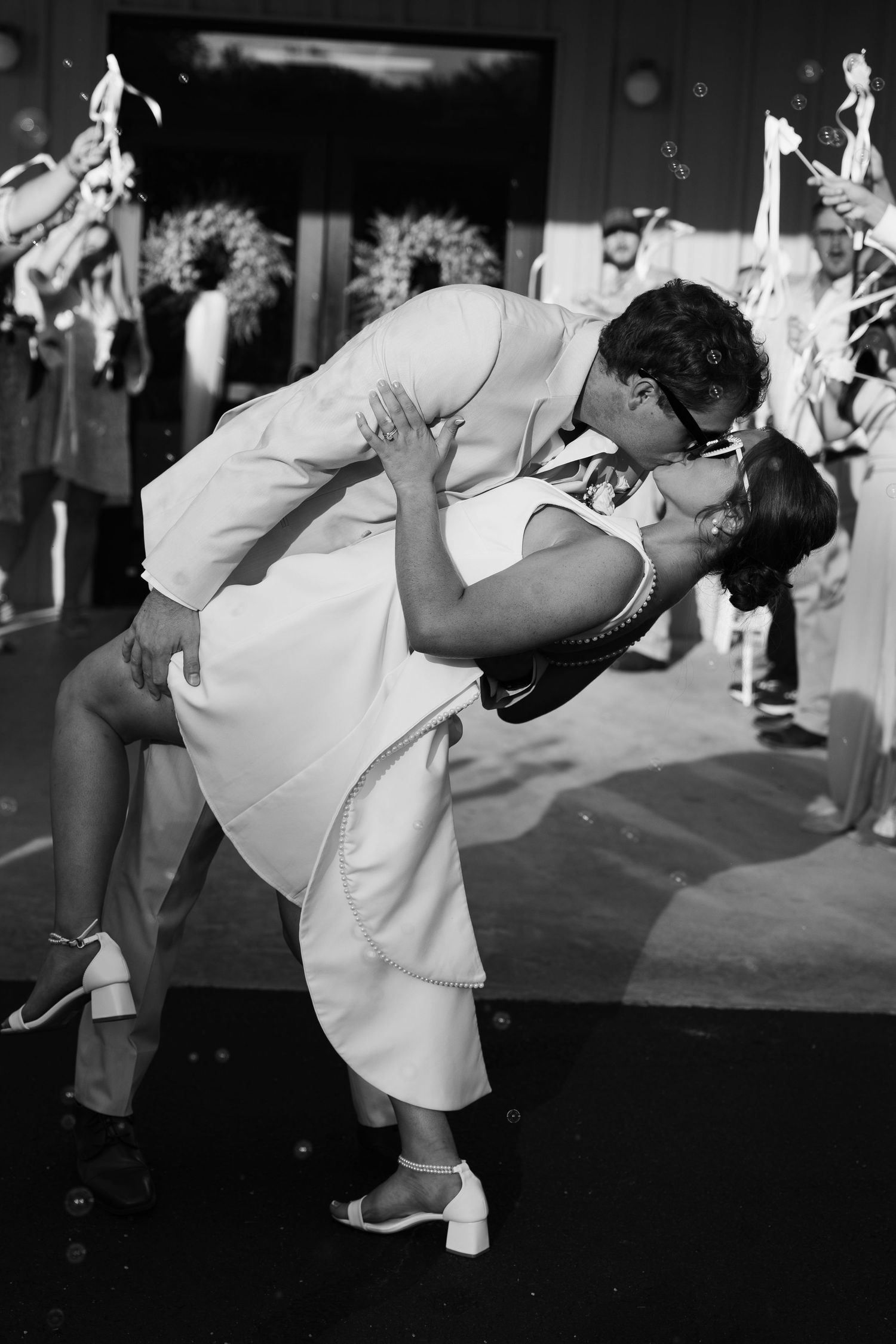 Black and white photo of newlyweds sharing a romantic dip kiss on the dance floor at their wedding reception.
