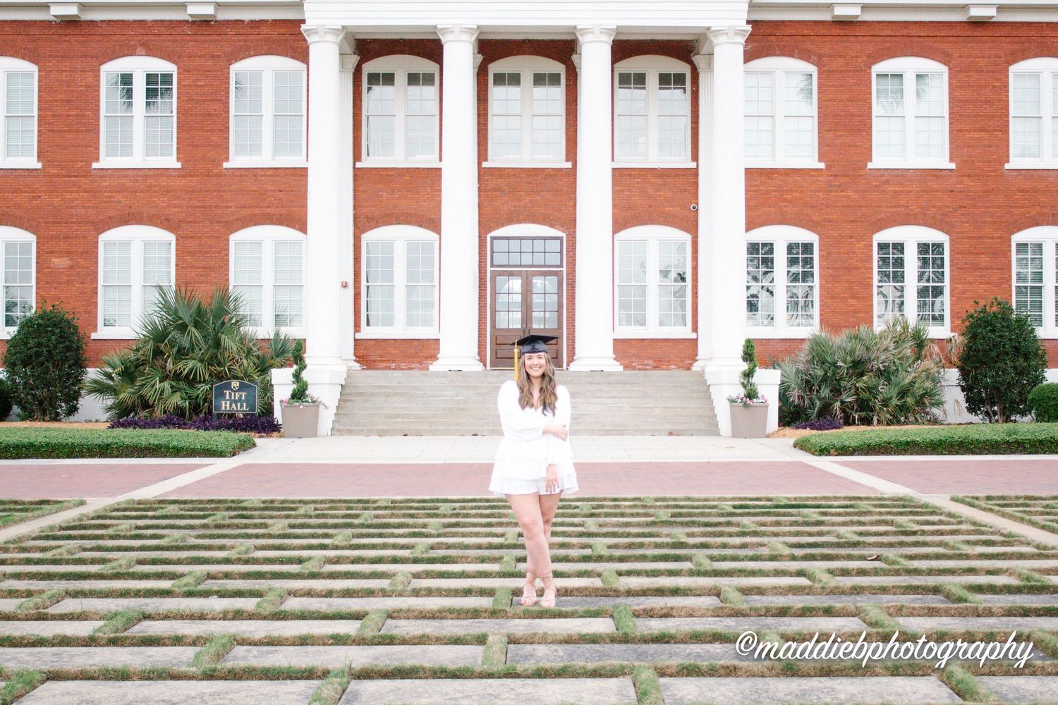 Red brick building with white columns and stairs creates an elegant architectural backdrop.