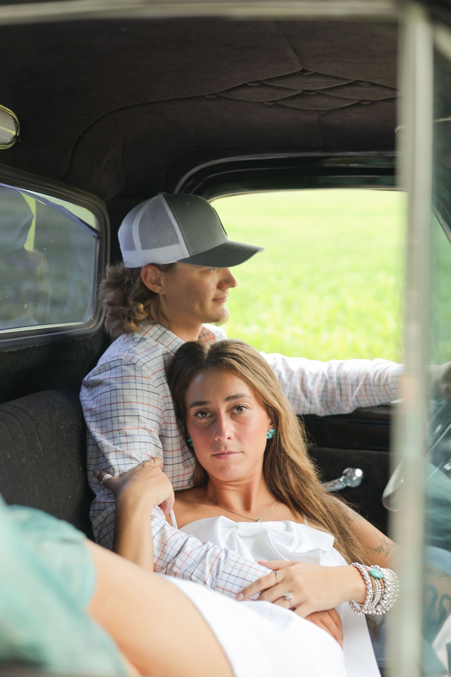 A romantic scene unfolds inside a classic car with natural light streaming in.