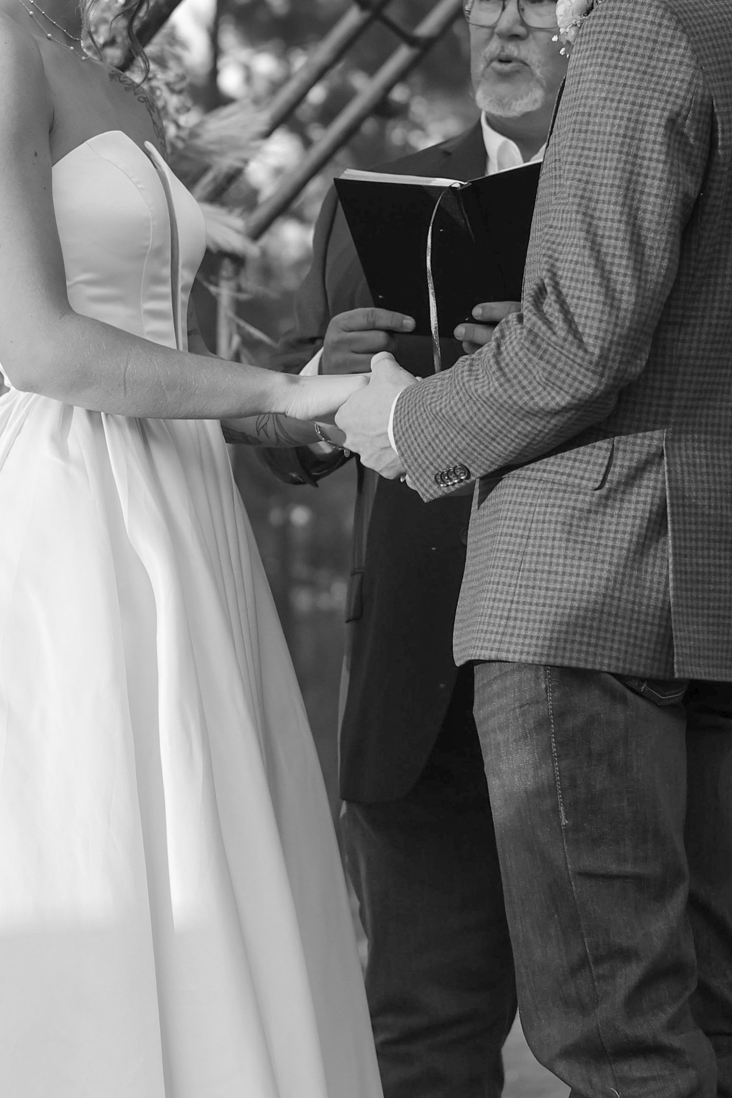 Close-up of wedding ceremony participants holding books during an outdoor service.
