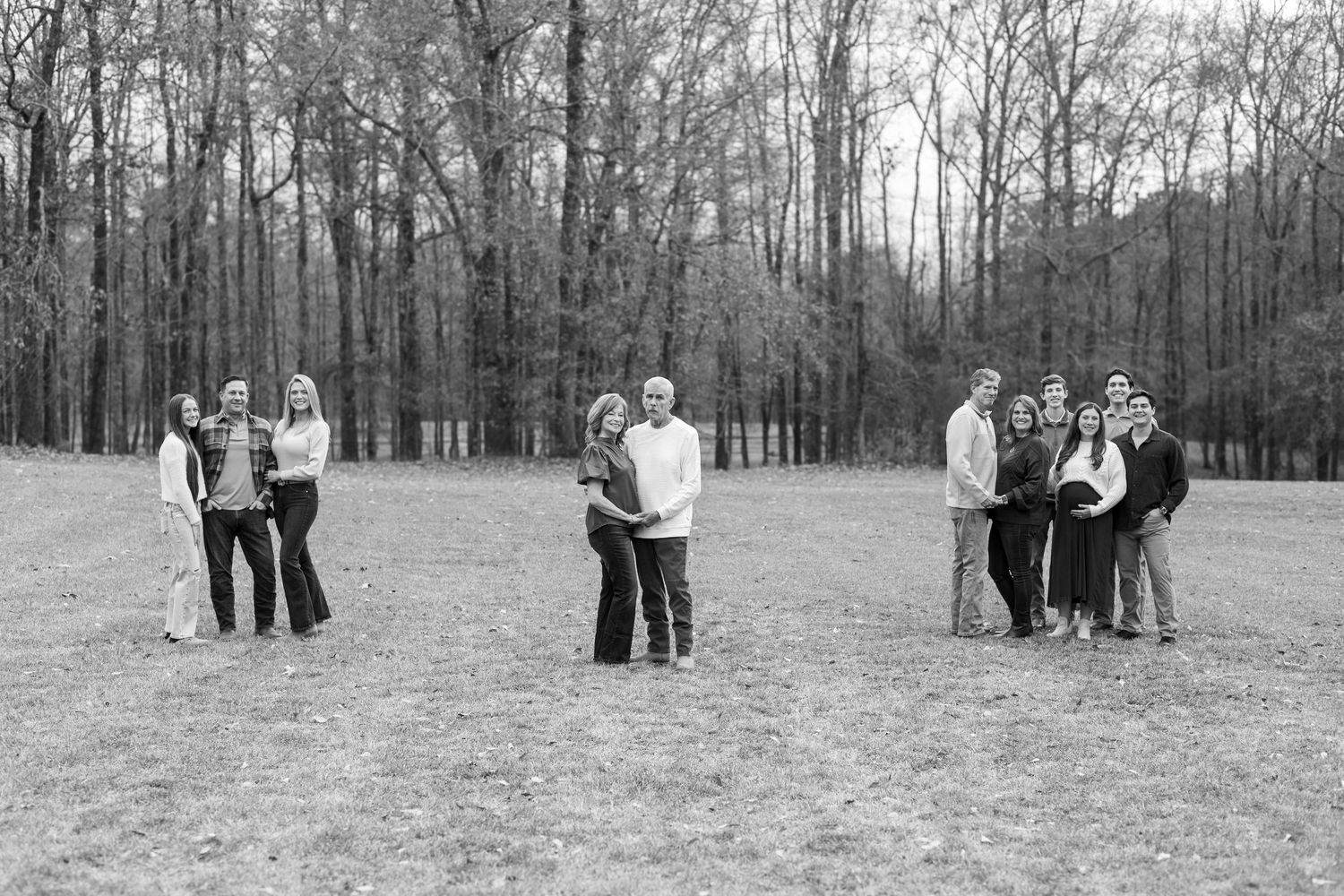 Black and white photograph of three couples standing together in a clearing surrounded by bare winter trees.
