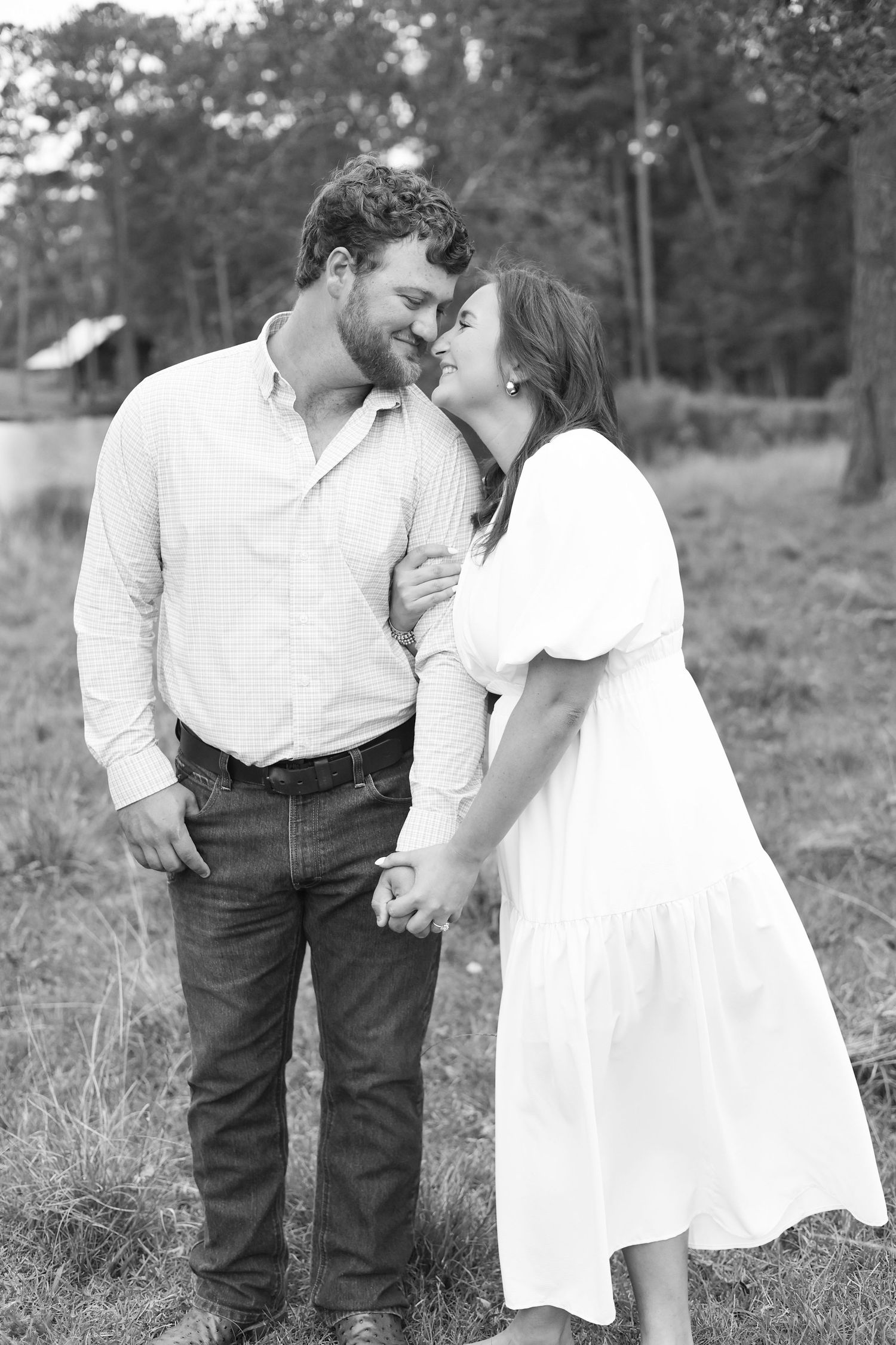 A romantic black and white portrait of a couple in casual attire sharing an intimate moment.