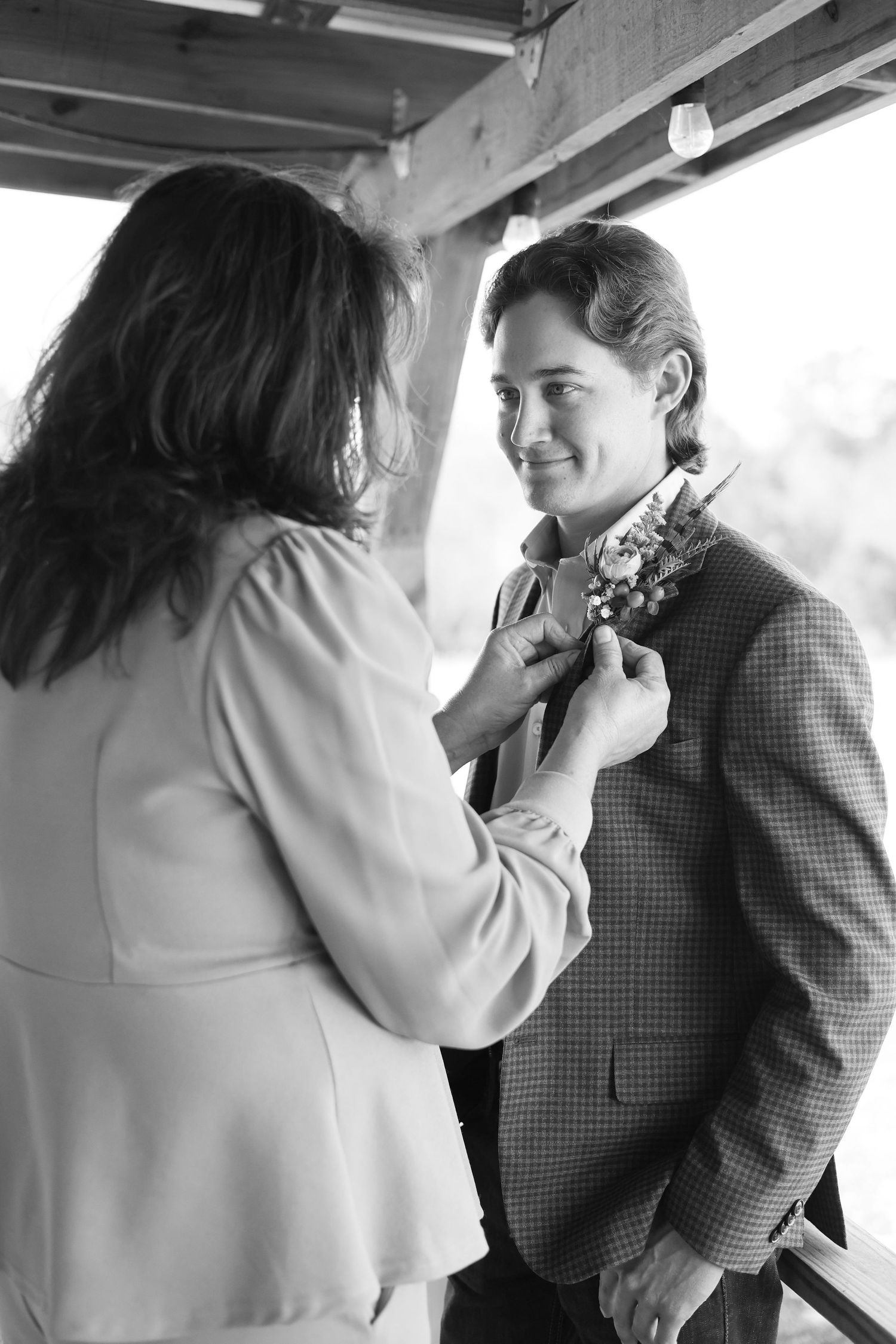 A boutonniere being pinned onto a checkered suit jacket.