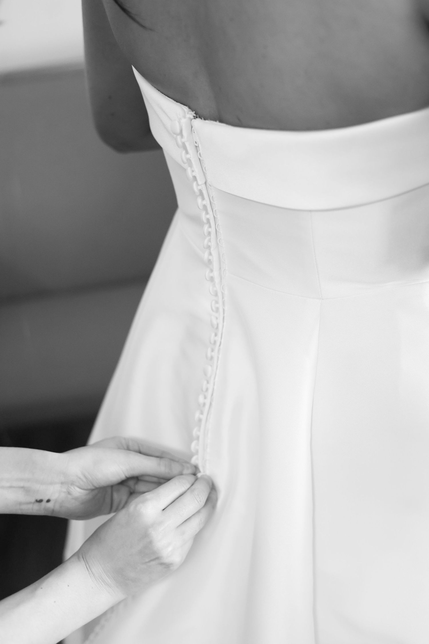 Close-up details of a white wedding dress showing buttons and lace details along the back.