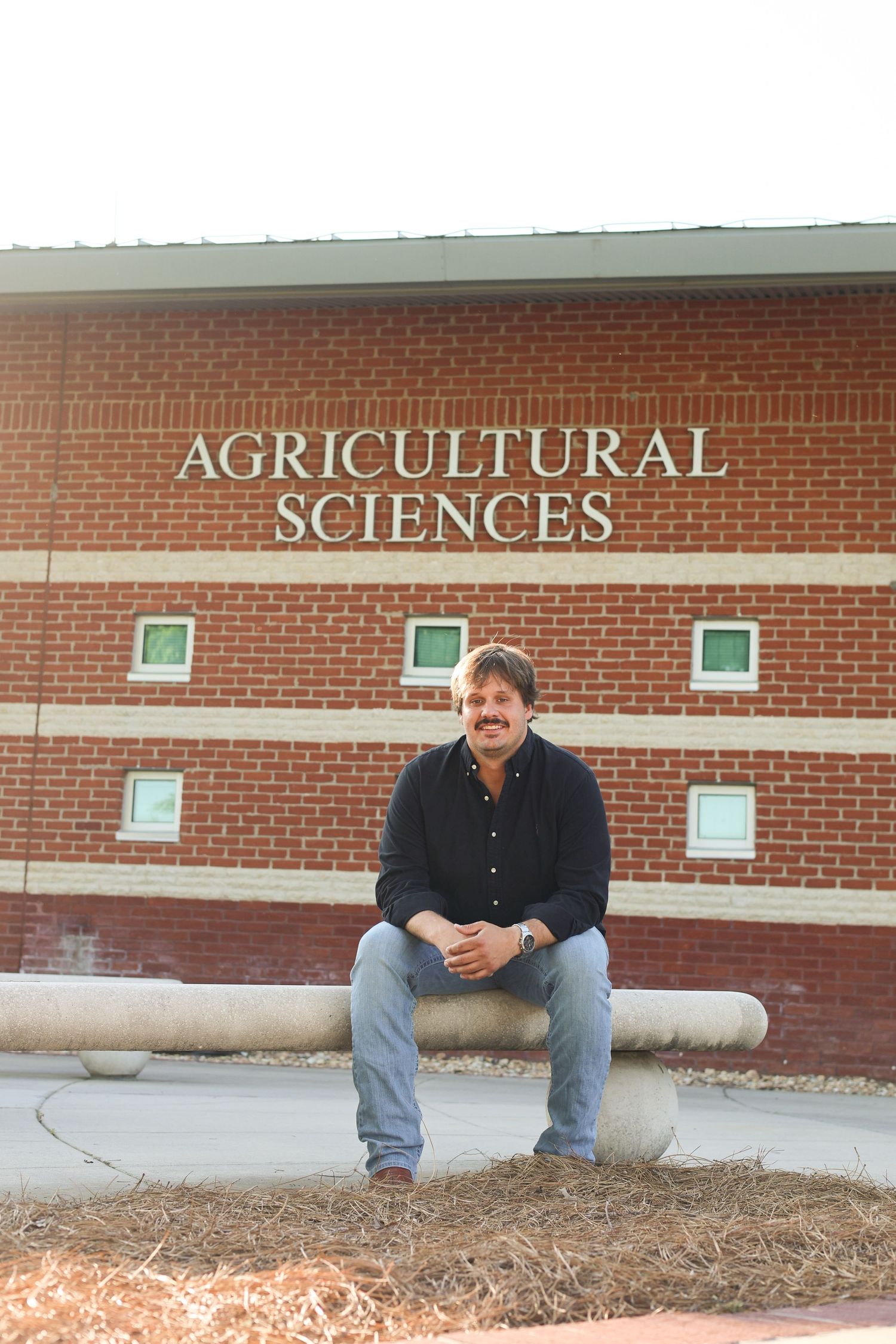 Student poses outside Agricultural Sciences building with red brick facade.