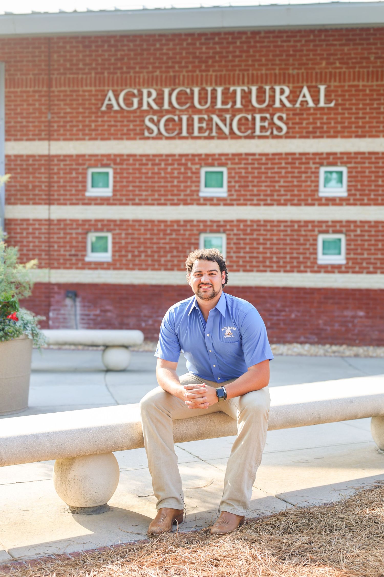 Person sits on concrete barrier outside Agricultural Sciences building.