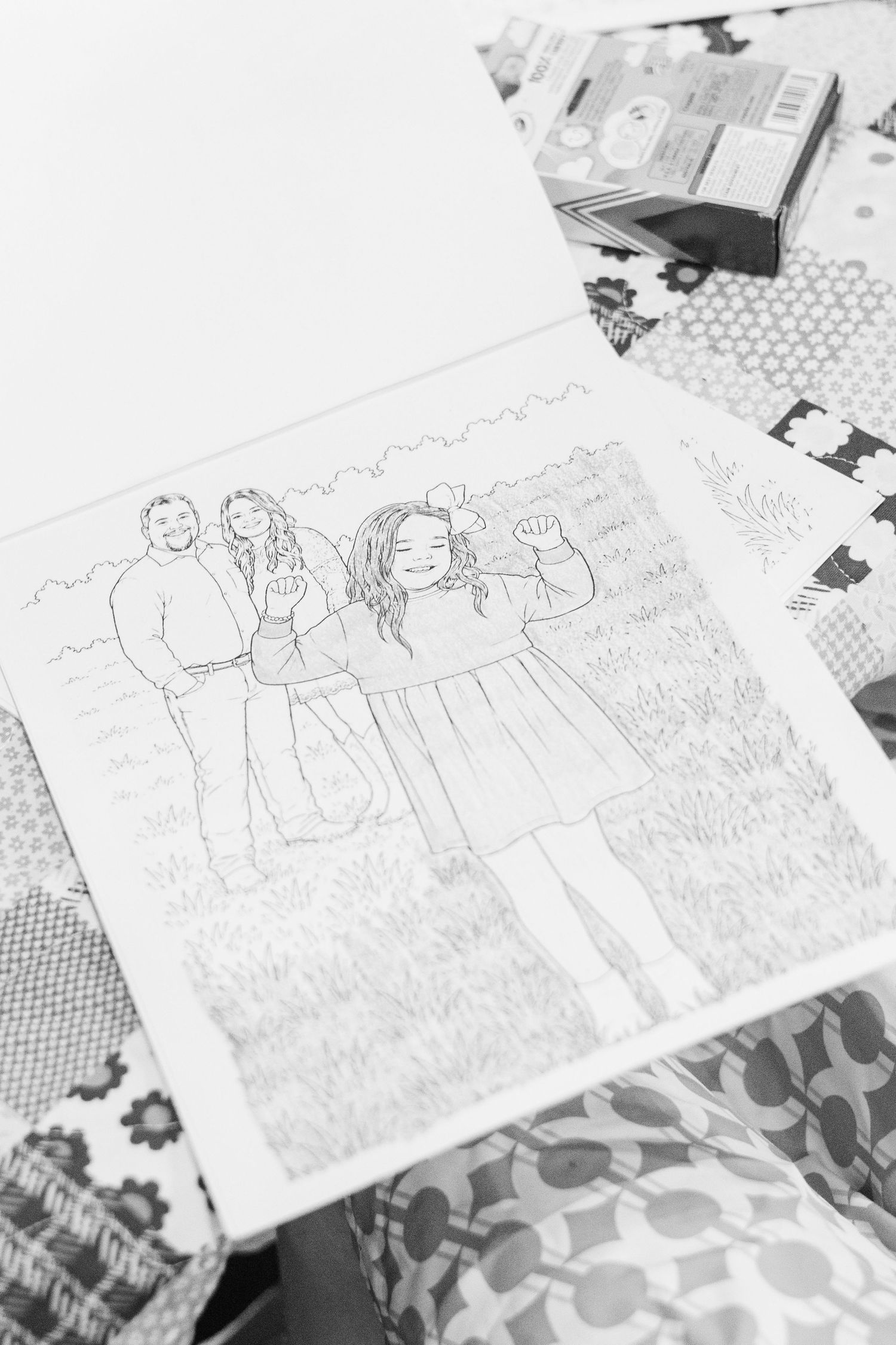 Black and white sketch of a family portrait drawn in a coloring book style on a patterned surface.