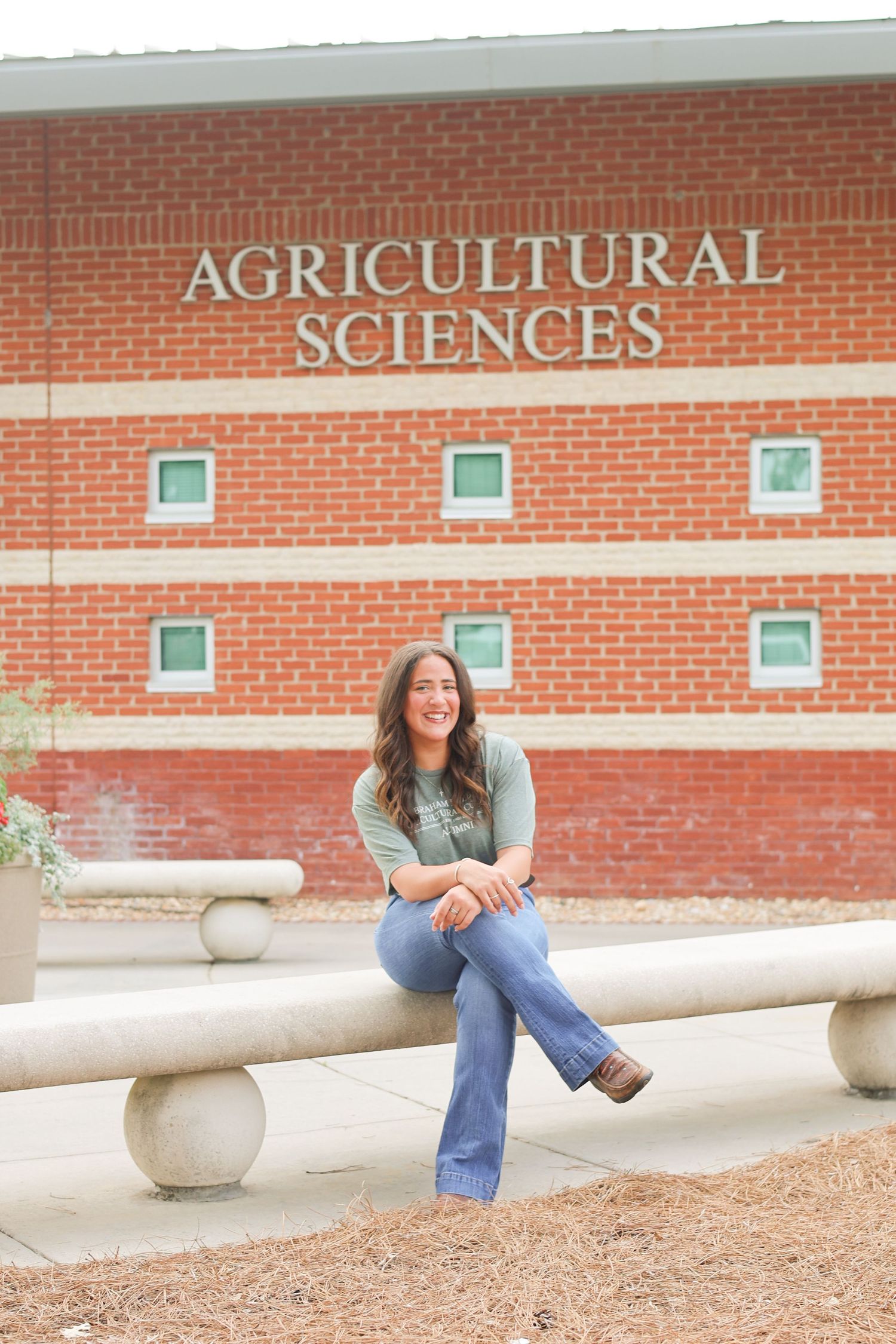 Person sitting casually on concrete bench outside Agricultural Sciences building.