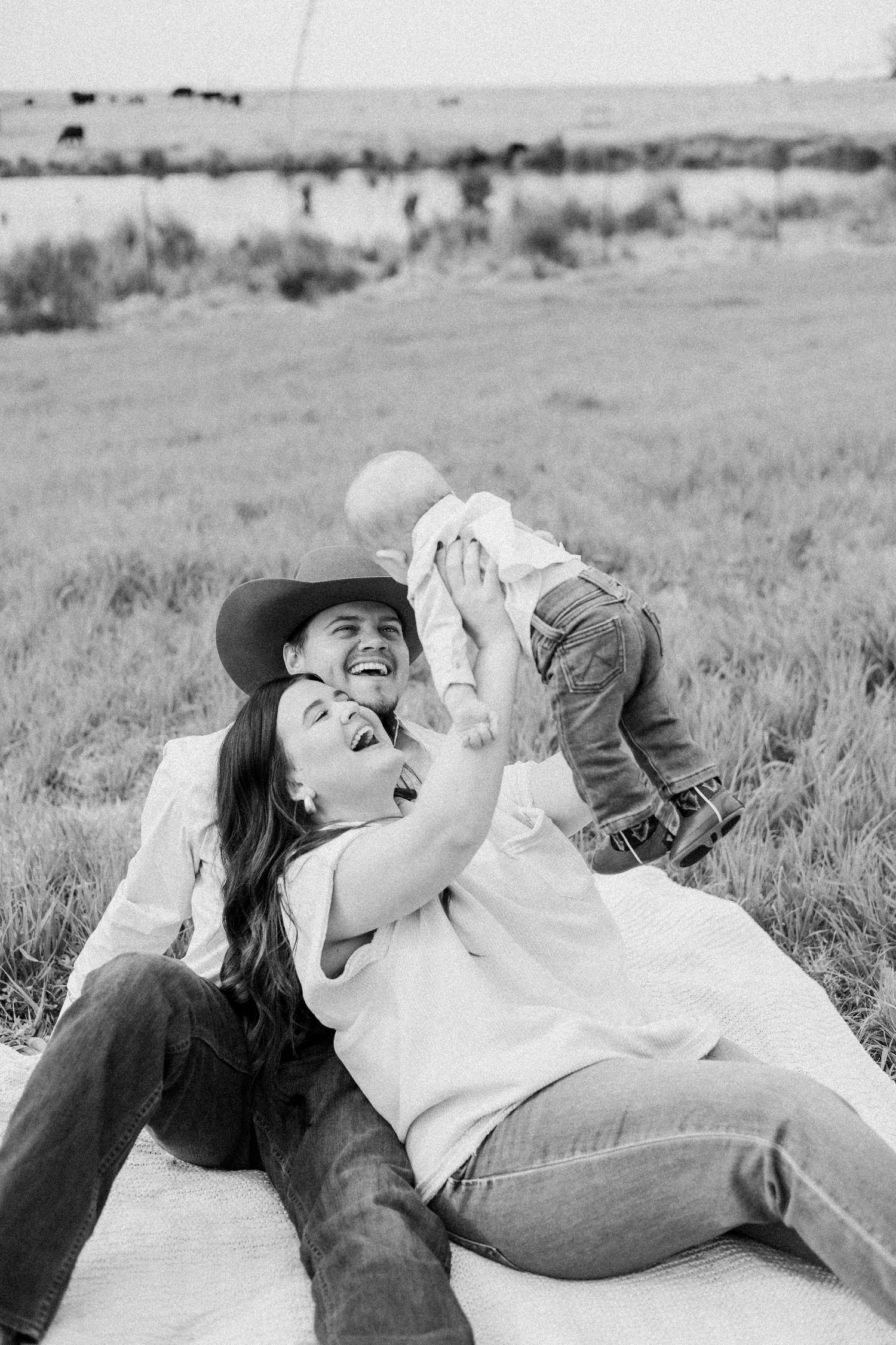 A family sharing joyful moments while lying on a blanket in a field.