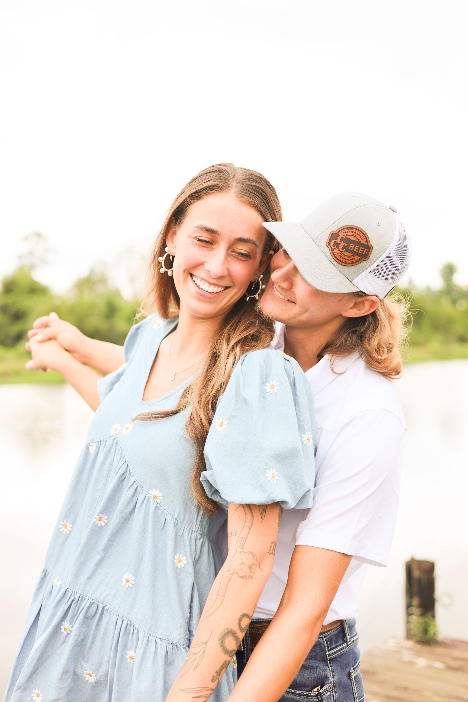 Couple sharing tender moments wearing casual summer outfits against natural backdrop.