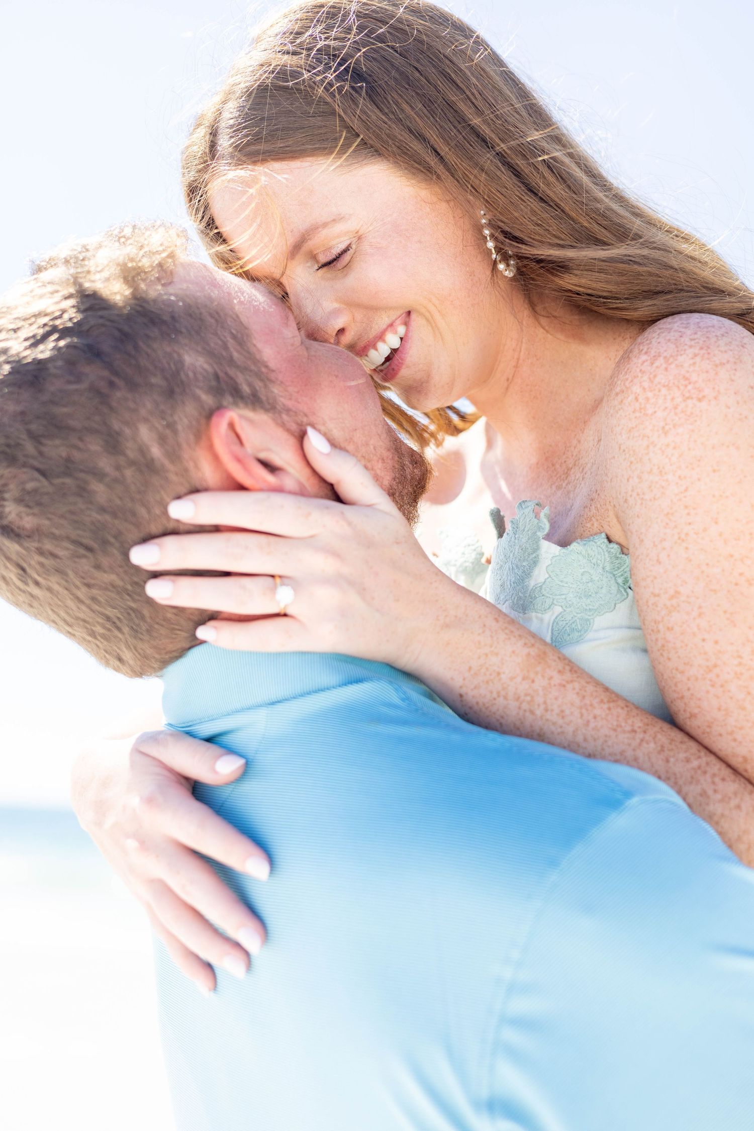 An intimate moment shared between a couple during a beach photoshoot.