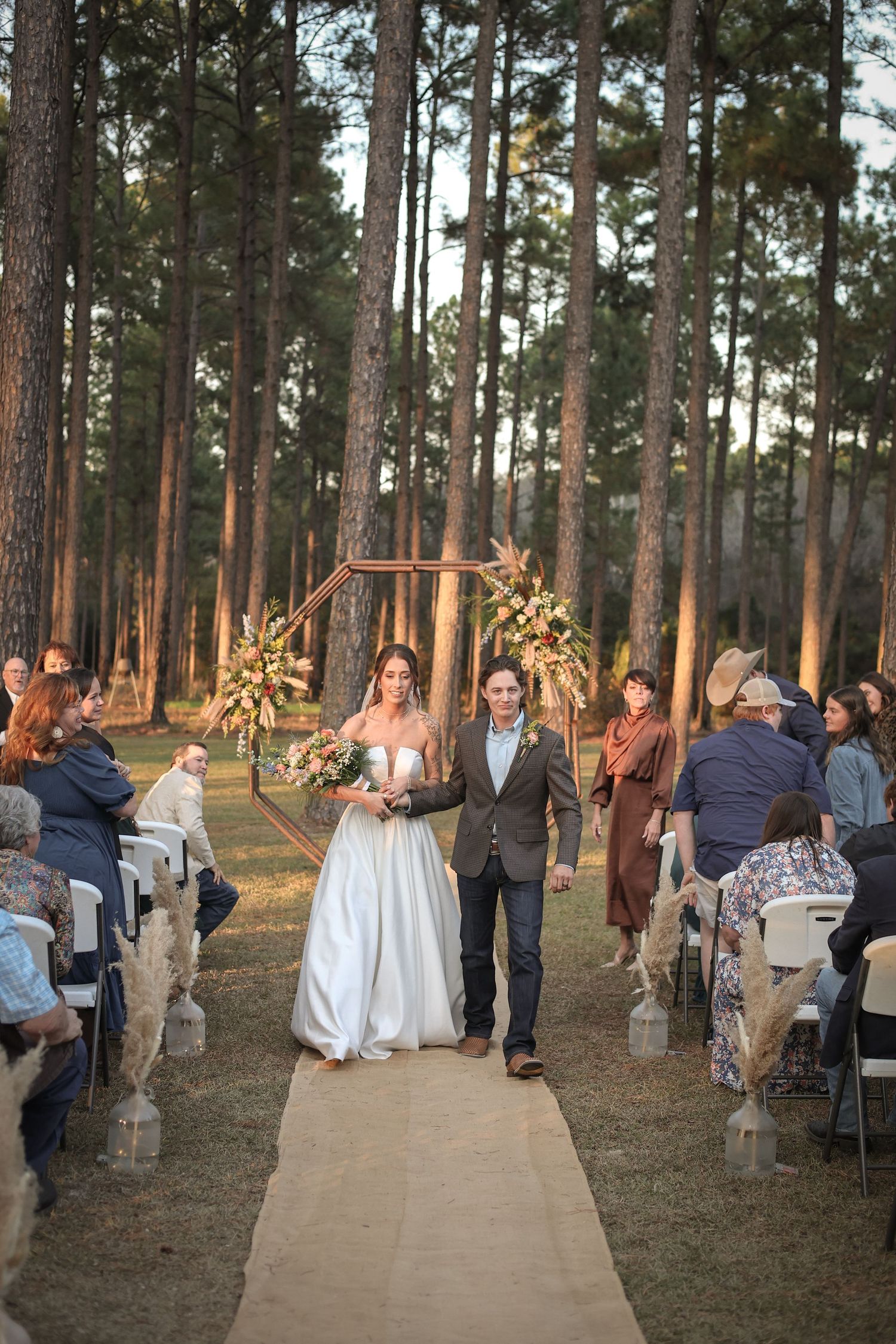 Wedding party and guests celebrating on a pathway through a pine forest.