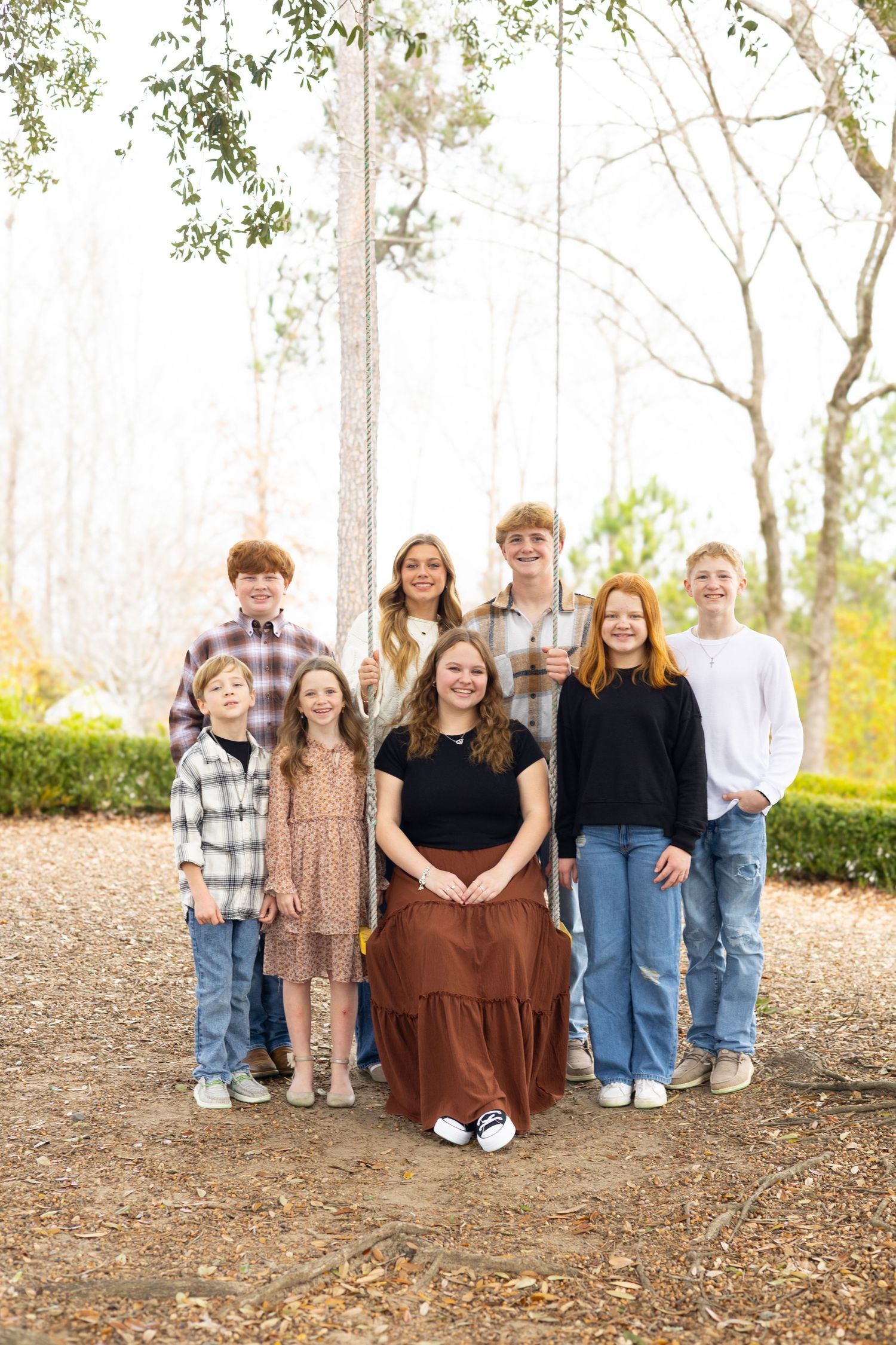 A group of young people standing together outdoors on a dirt path with trees in the background.