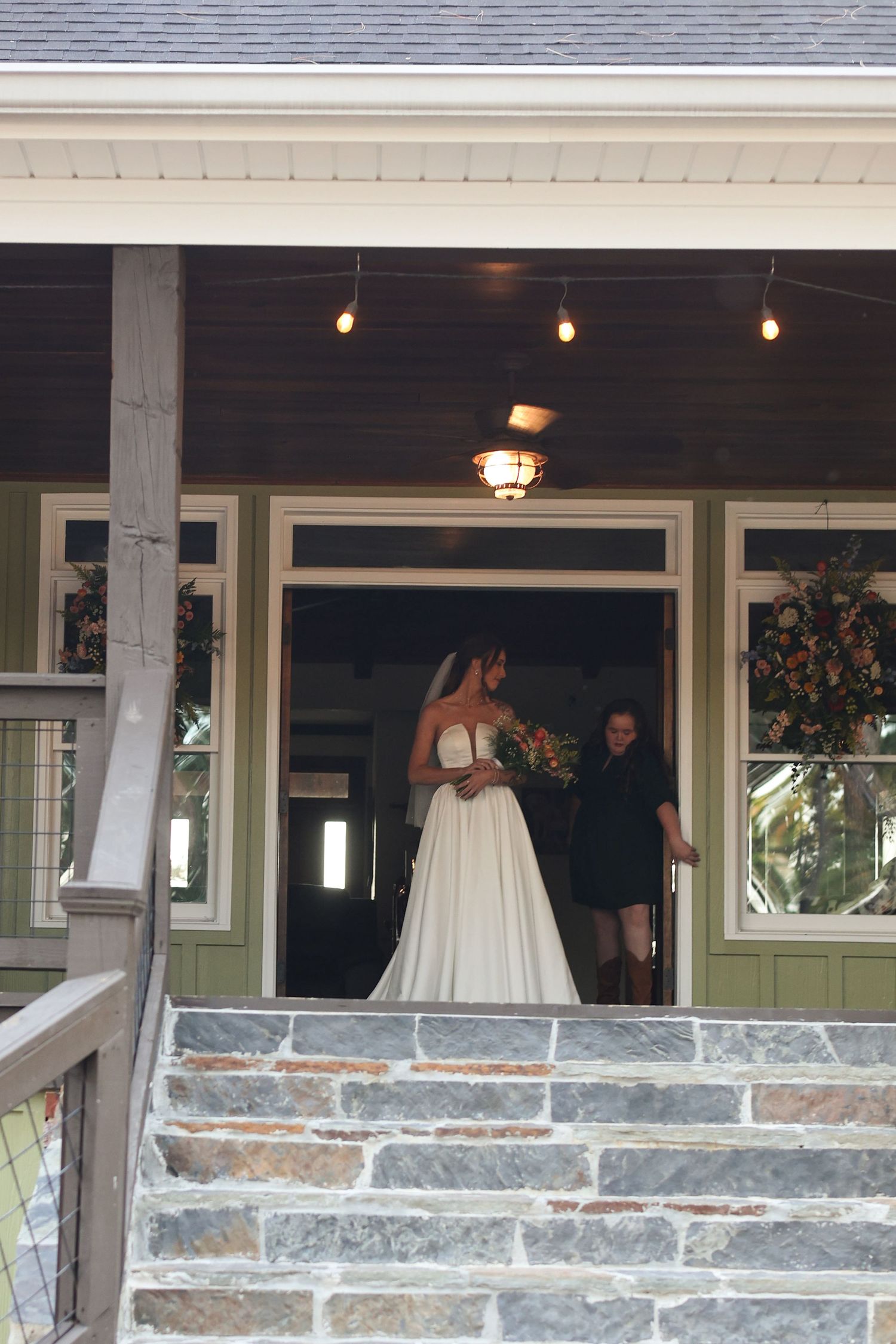 A stone-front wedding venue with steps and large windows decorated with string lights.