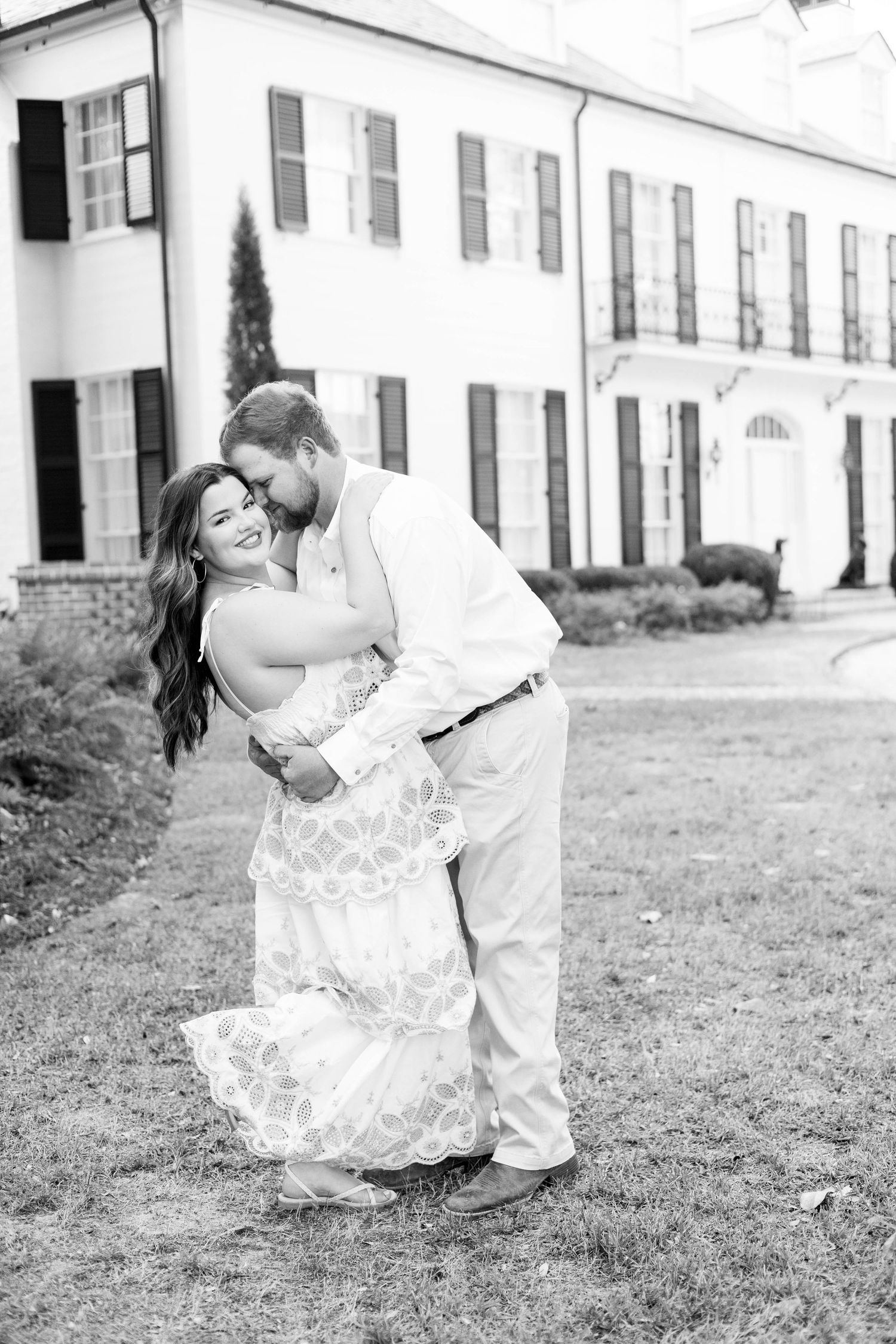 Couple dancing and dipping on grassy lawn in romantic black and white photo sequence.