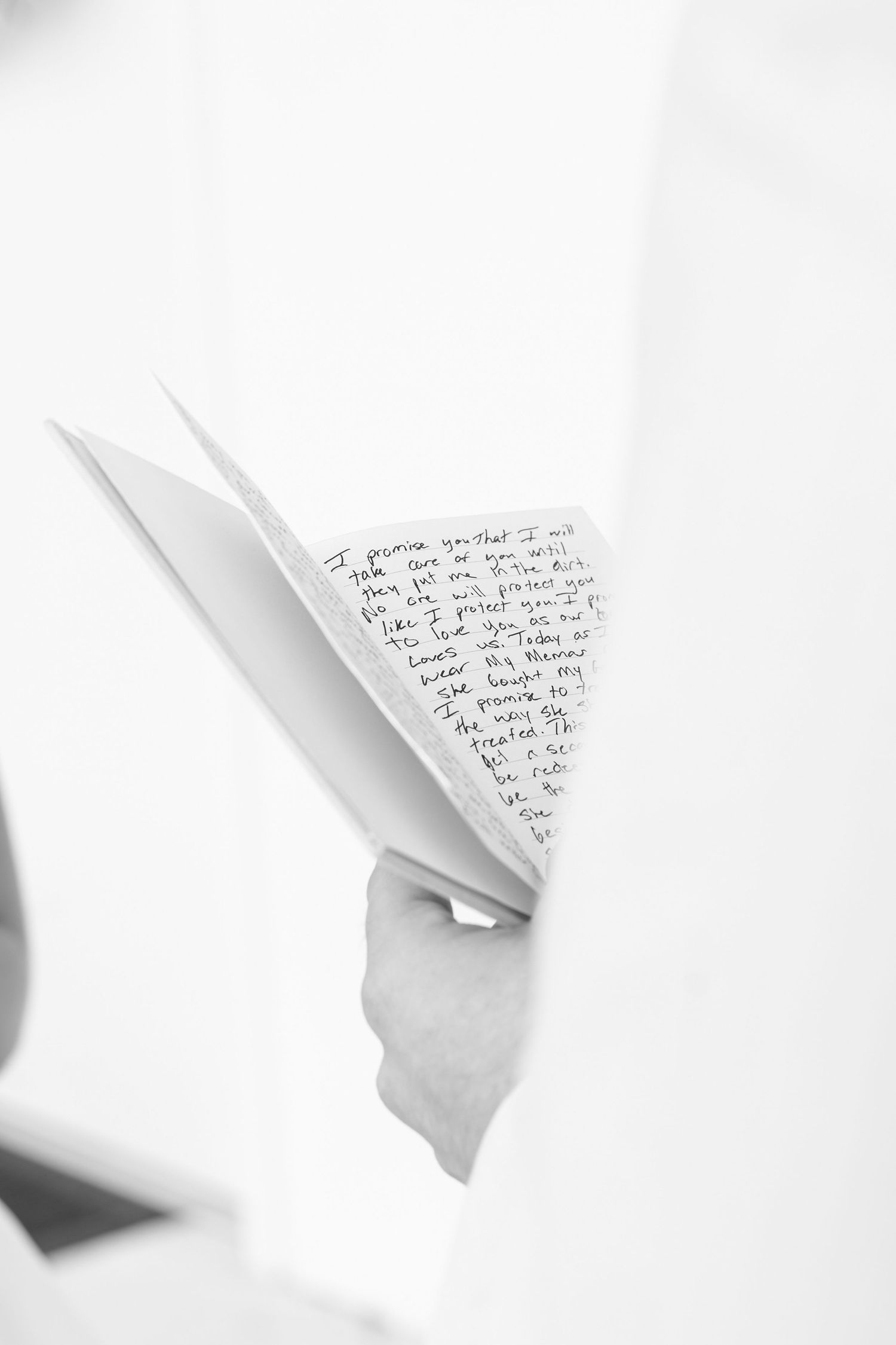 Close-up of handwritten wedding vows letter held by groom before ceremony.