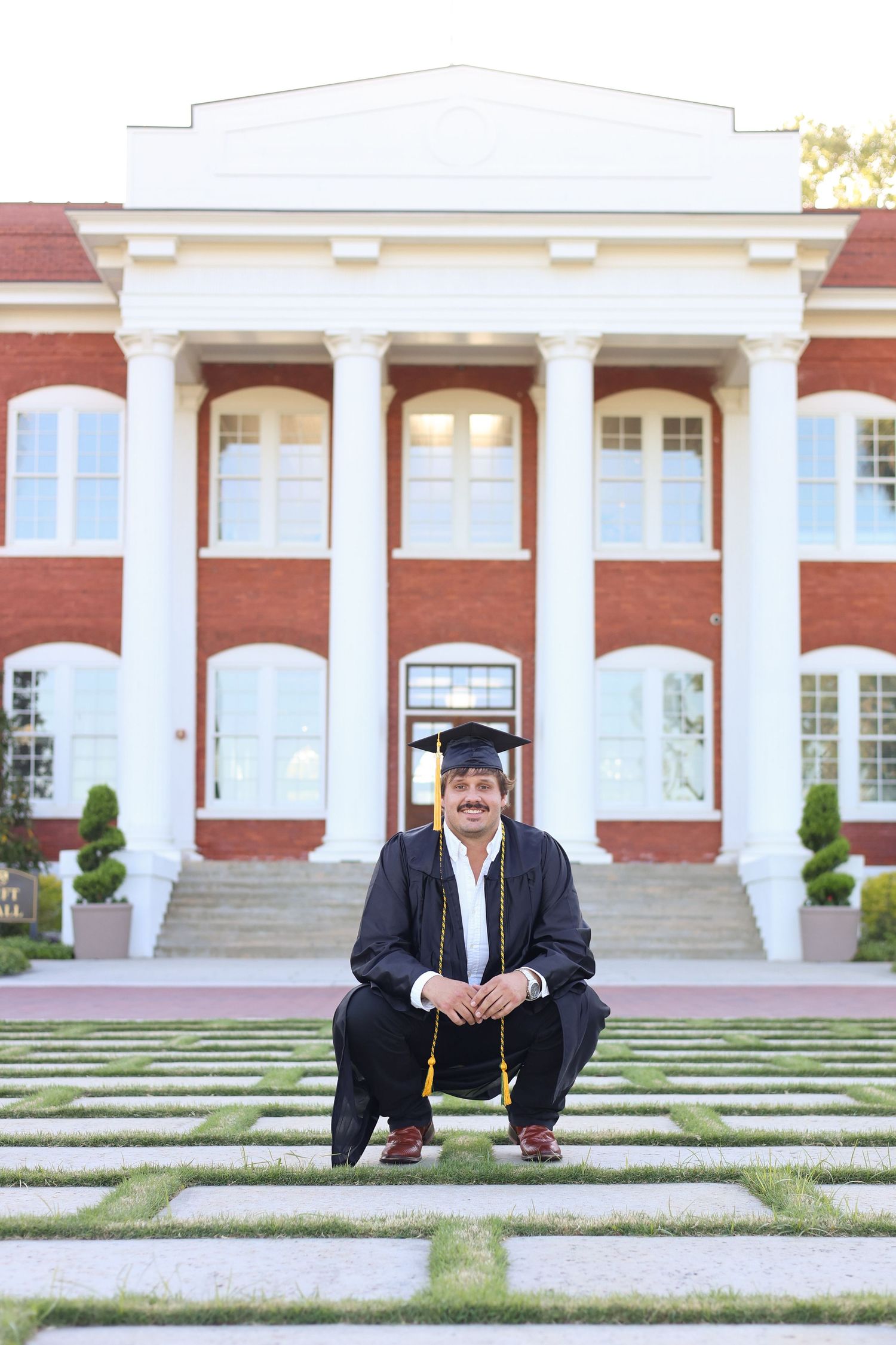 Graduate portrait session in front of red brick university building with white columns.