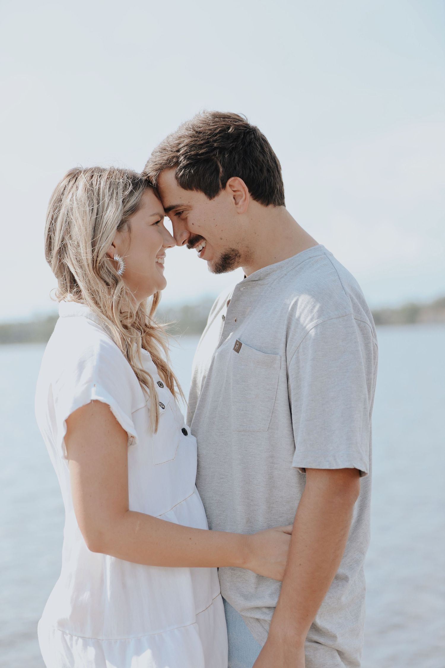 A romantic couple shares an intimate moment by the water during sunset.