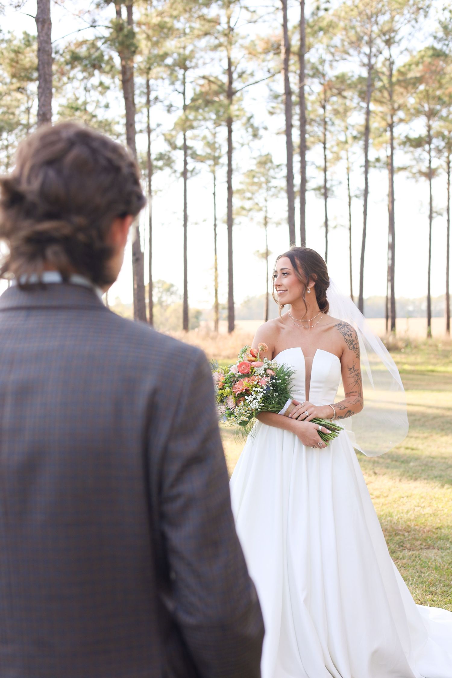 A couple shares a romantic moment among tall pine trees during their wedding photoshoot.