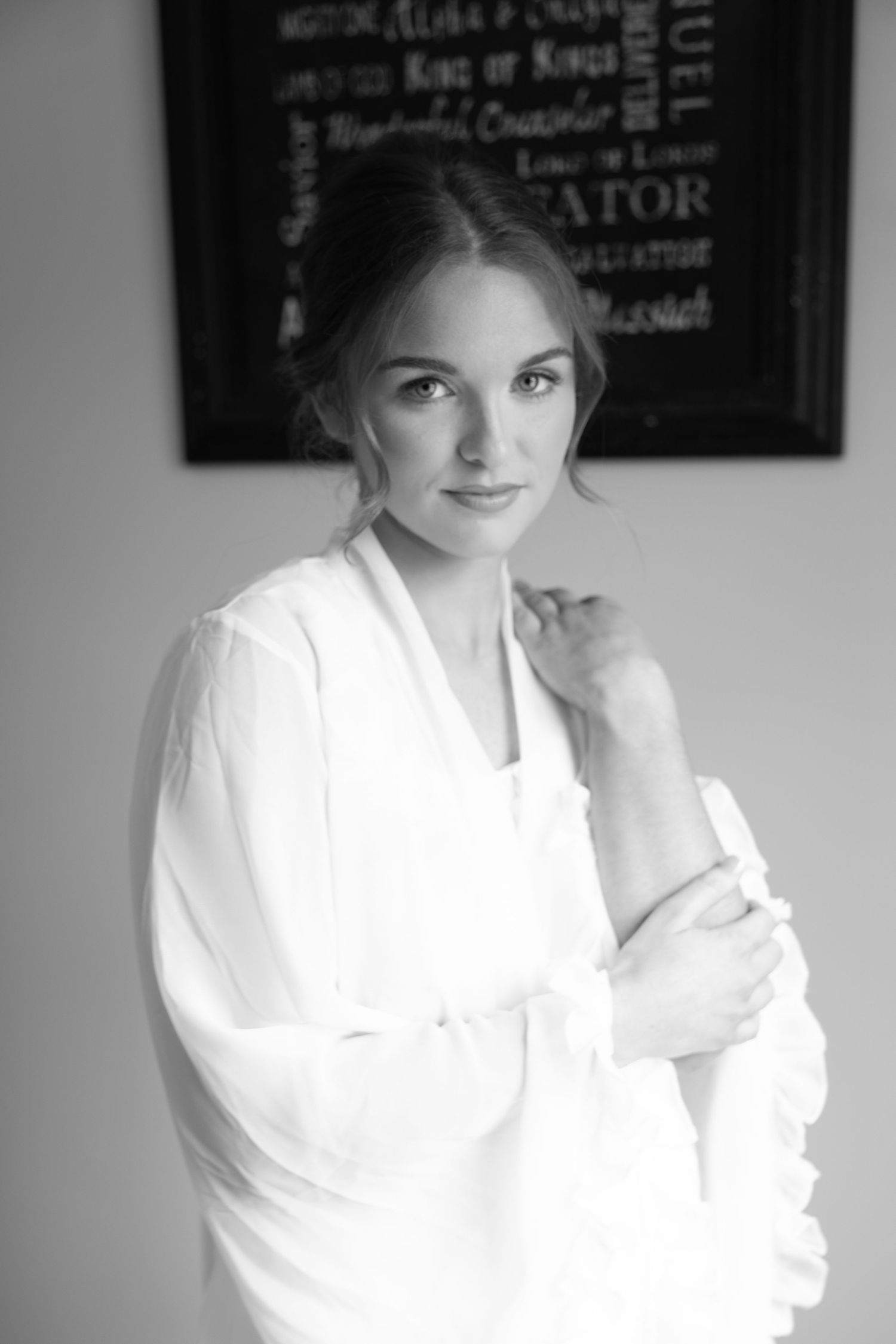 Elegant bride in white robe posing for black and white bridal portrait before wedding ceremony.