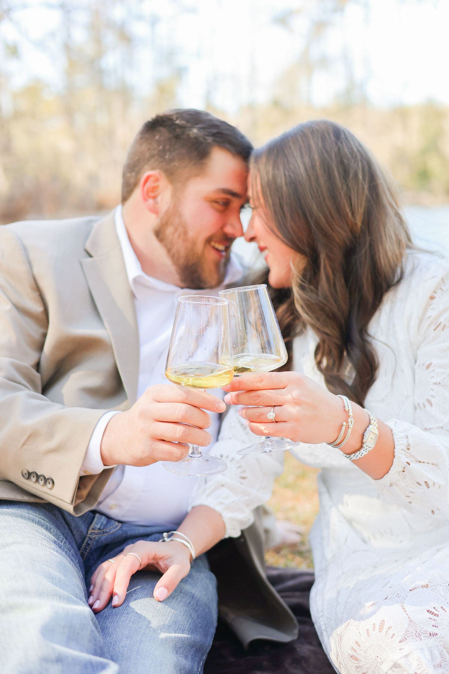 Romantic couple sharing wine glasses and intimate moment outdoors in casual elegant attire.