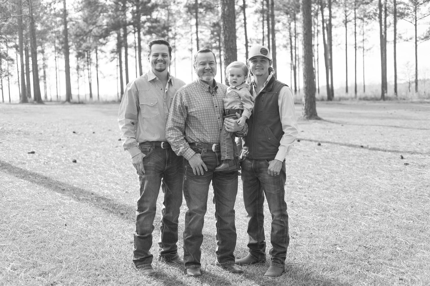Group portrait session outdoors with pine forest backdrop on sunny autumn day.