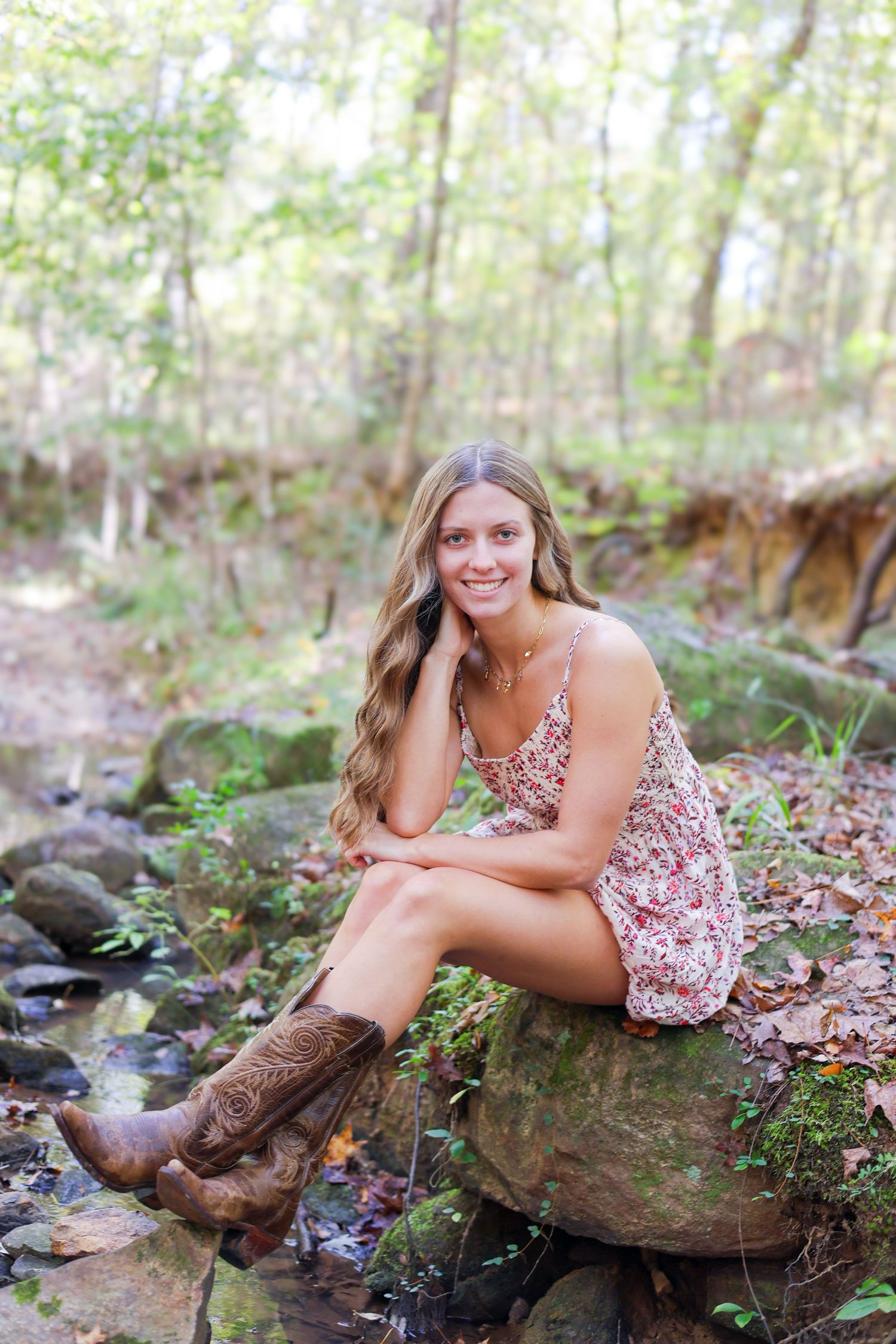 A dreamy woodland photoshoot featuring a floral sundress and cowboy boots by a creek.