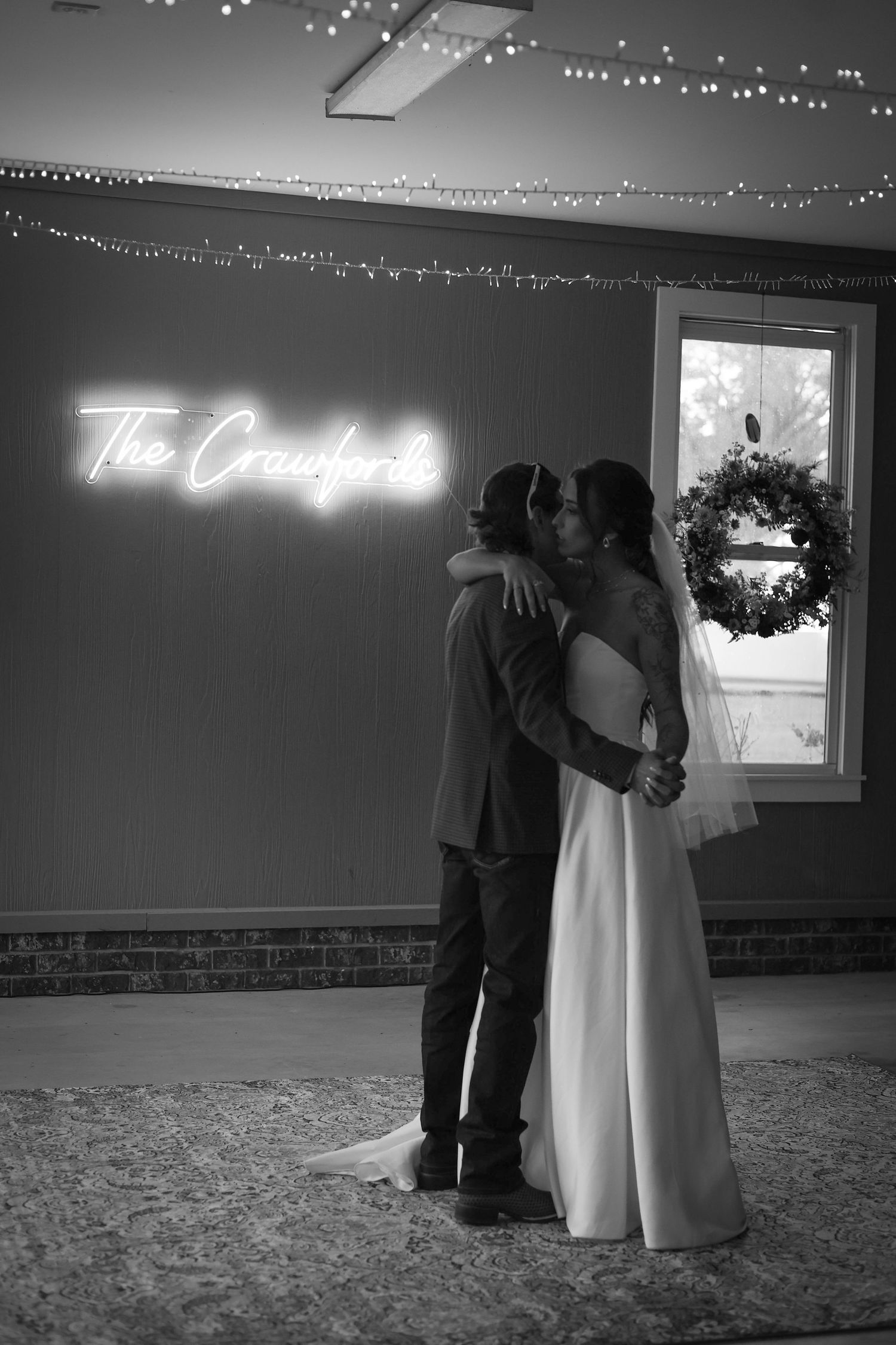 Wedding reception dance with string lights and neon sign in dark venue.