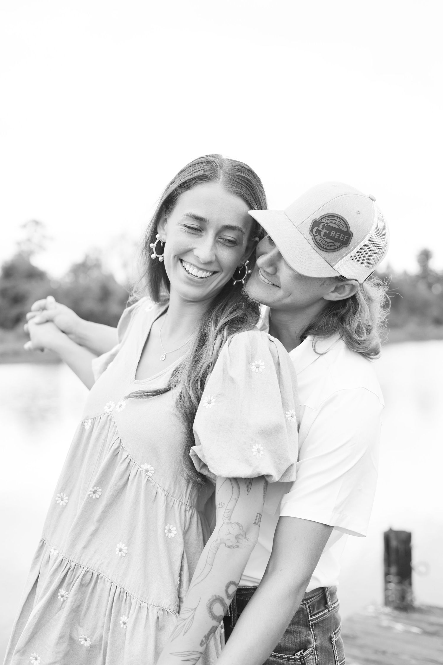 Black and white portrait of couple in casual attire sharing intimate moments outdoors.
