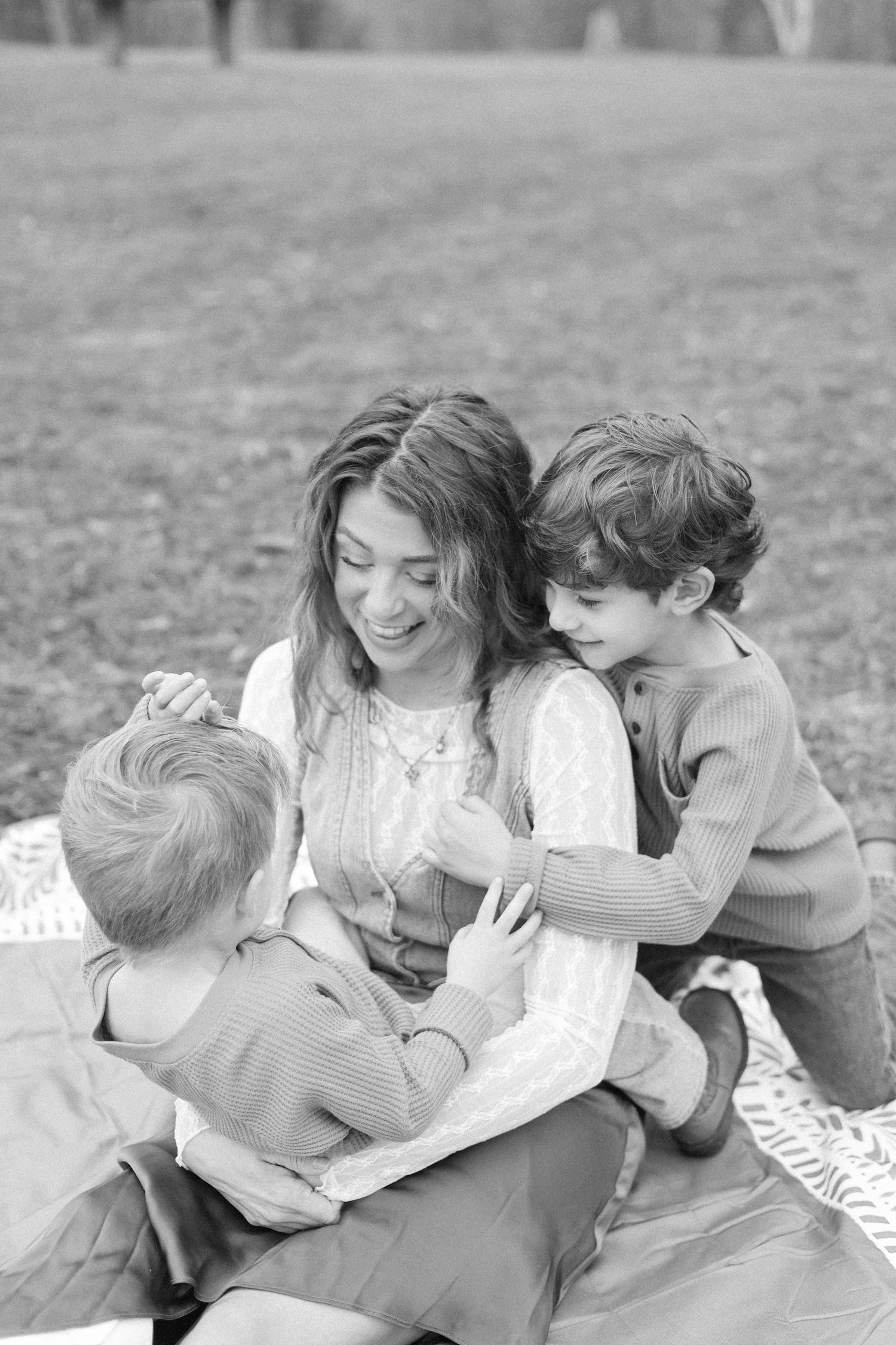 A heartwarming black and white photo series showing a family playing and laughing together outdoors on the grass.