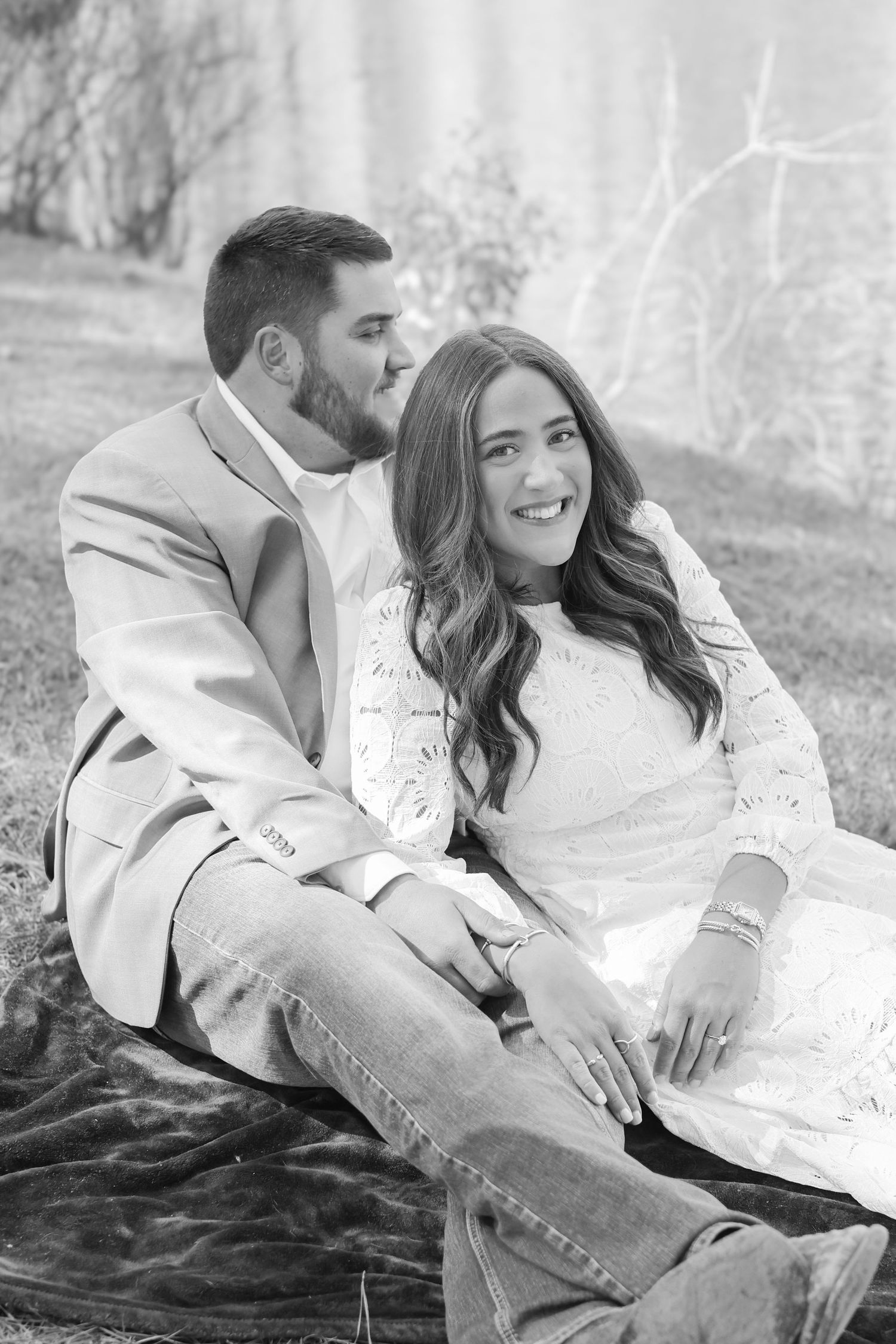 A couple in white and denim relaxing together on a blanket during an outdoor photoshoot.