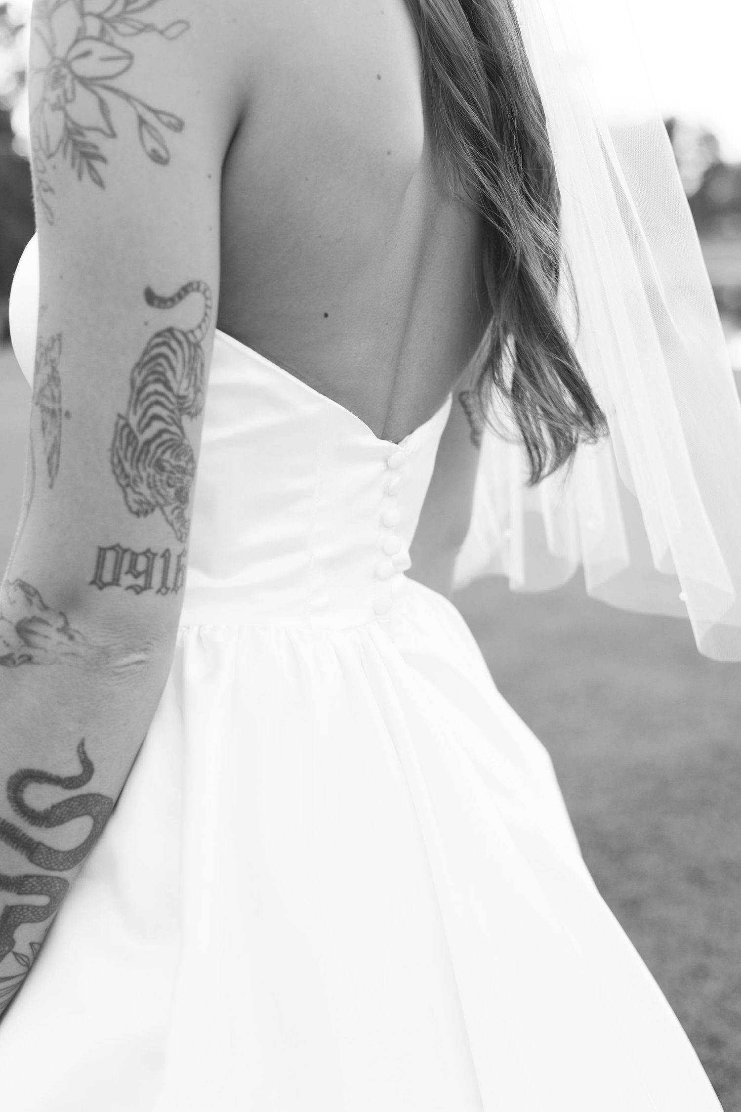 Black and white detail shots of wedding dress back and tattoo art.