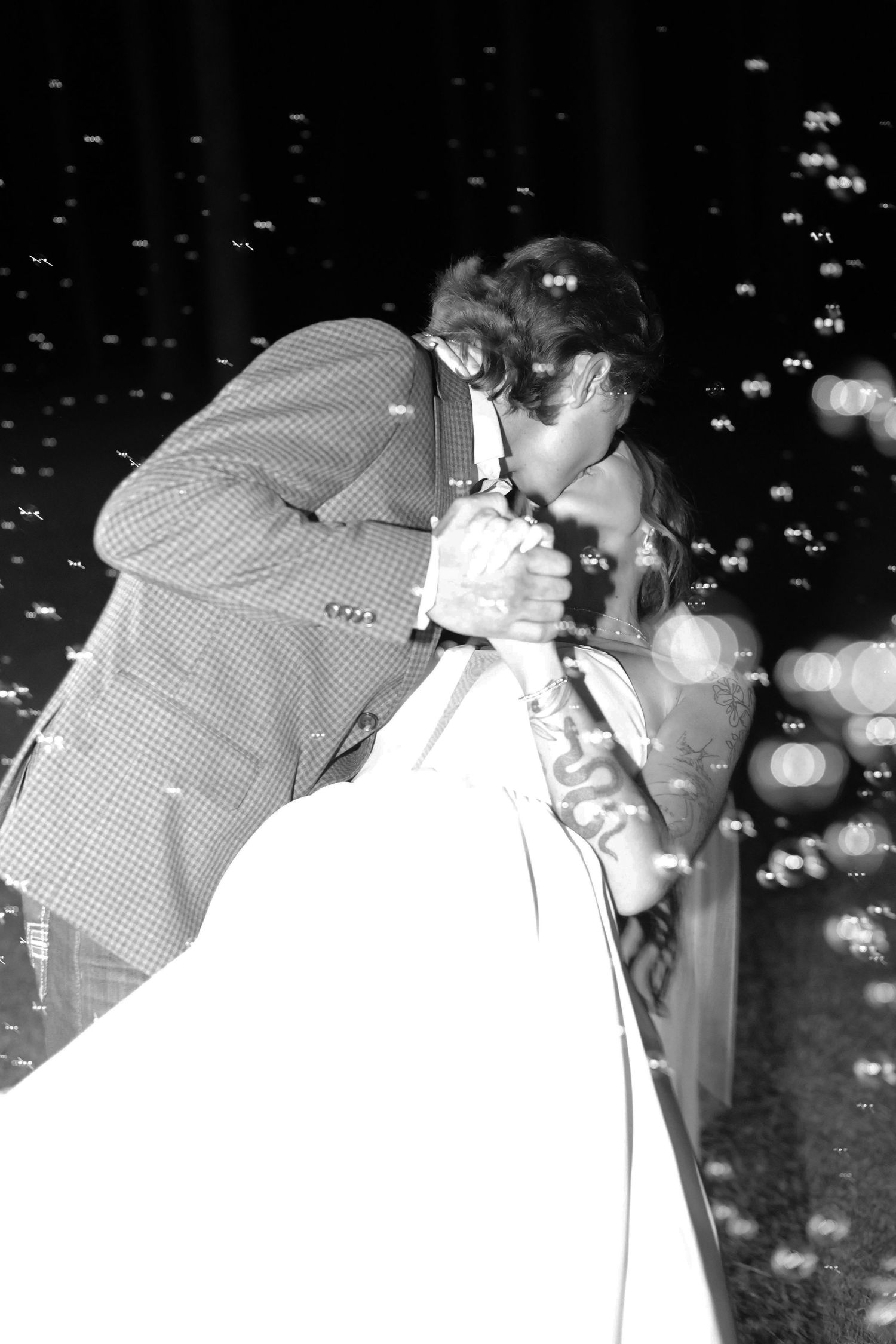 Black and white photos of a couple embracing with sparkling lights in the background.