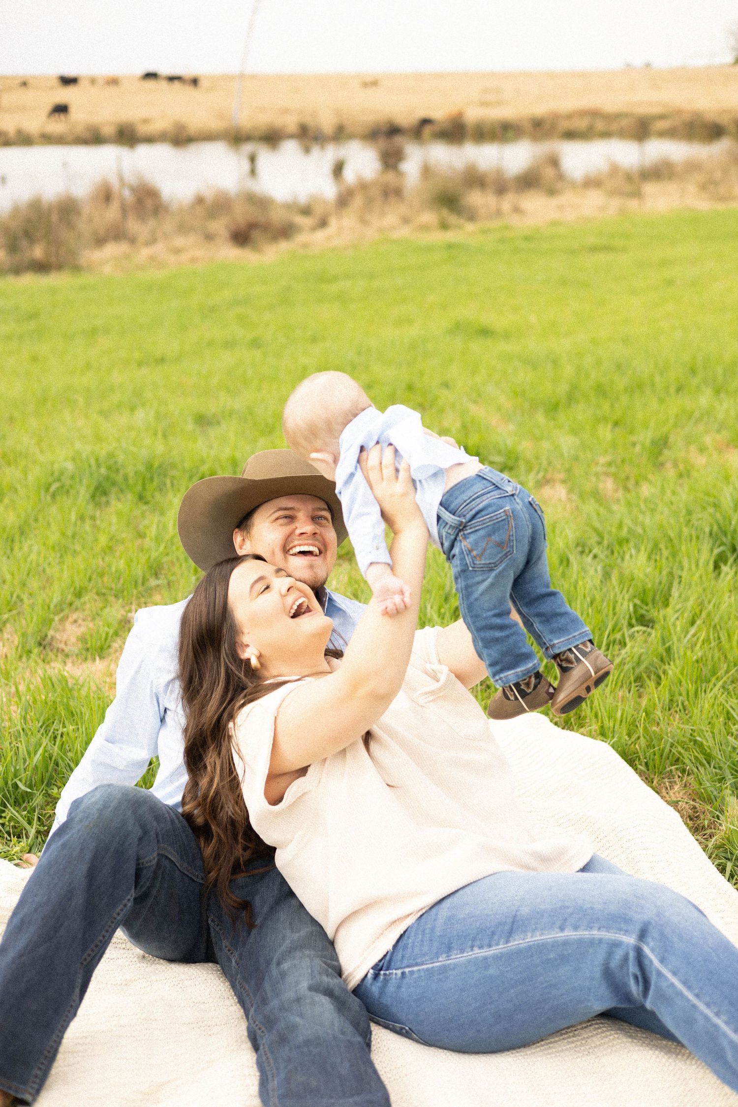 A happy family playing together on a blanket in a sunny meadow.