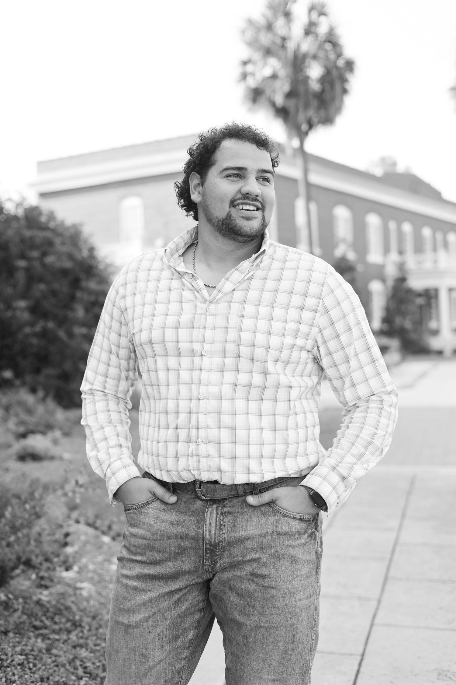 Casual outdoor portrait against brick building in plaid shirt and jeans.
