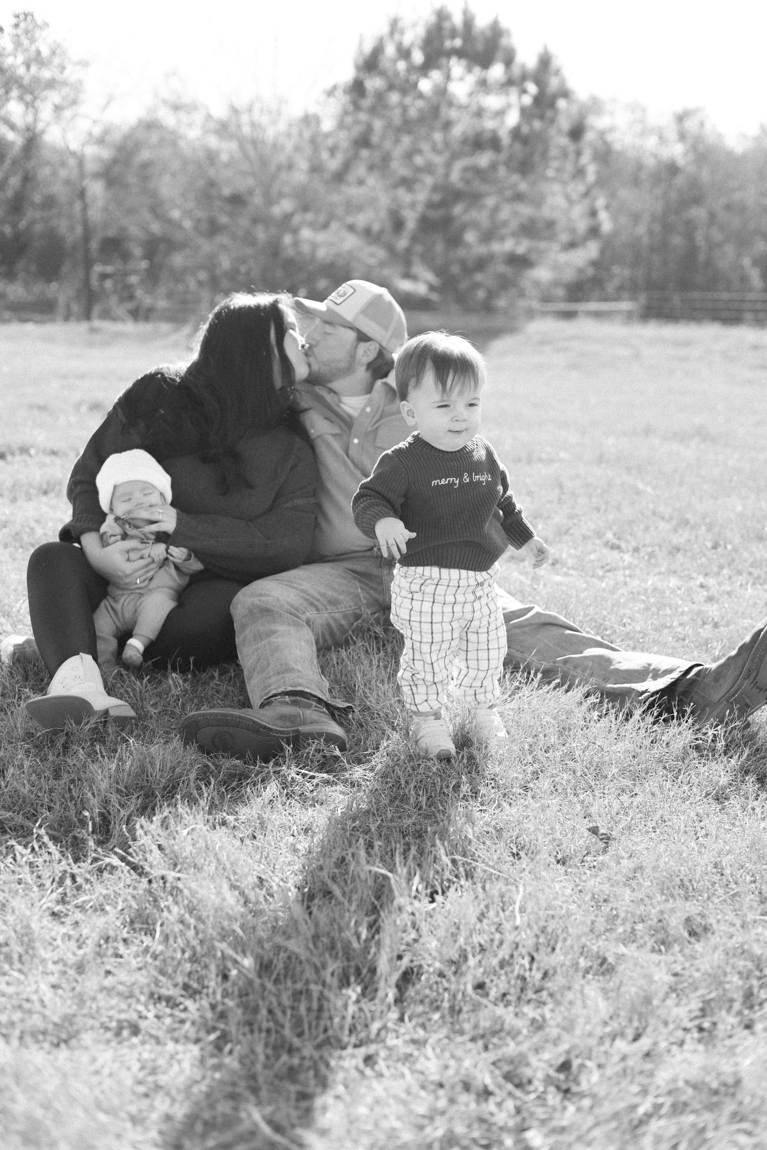 A couple lying together in a grassy field on a sunny day, shown in a series of black and white photographs.