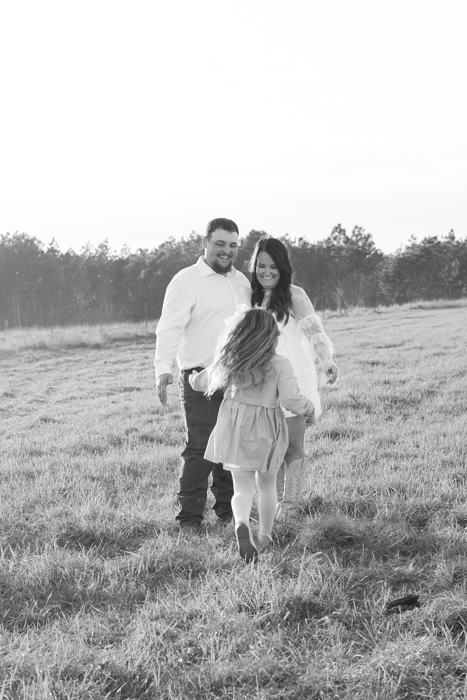 A couple shares a romantic moment together in a sunlit grassy field on a bright afternoon.
