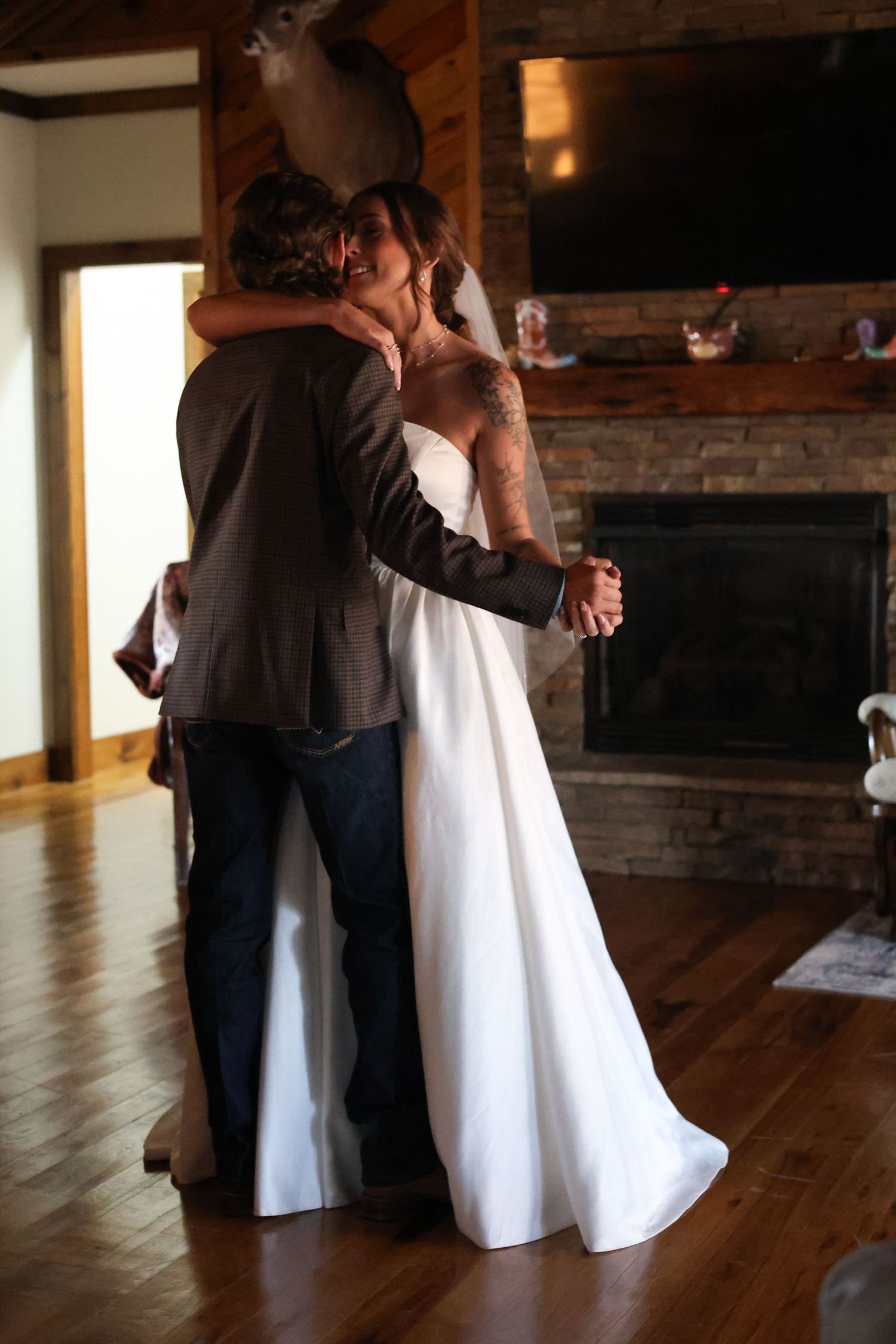 First dance moment on hardwood floors with brick fireplace in background.