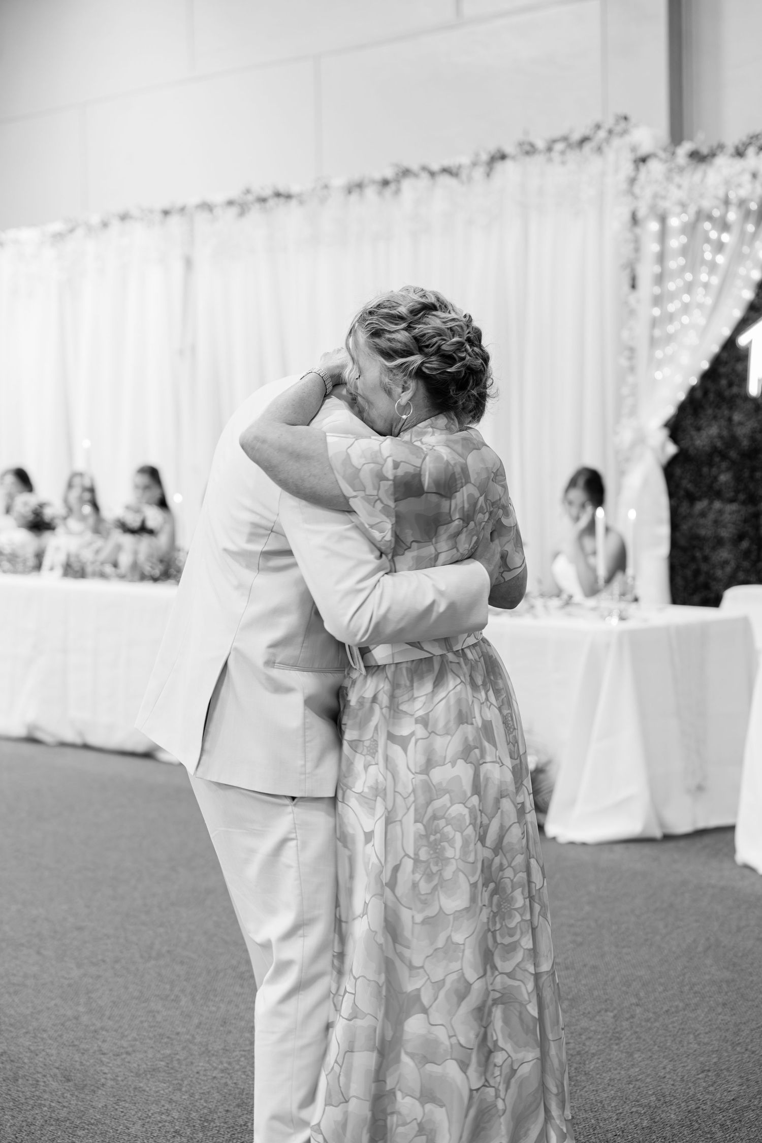 Groom tenderly embraces mother during emotional mother-son dance at wedding reception.
