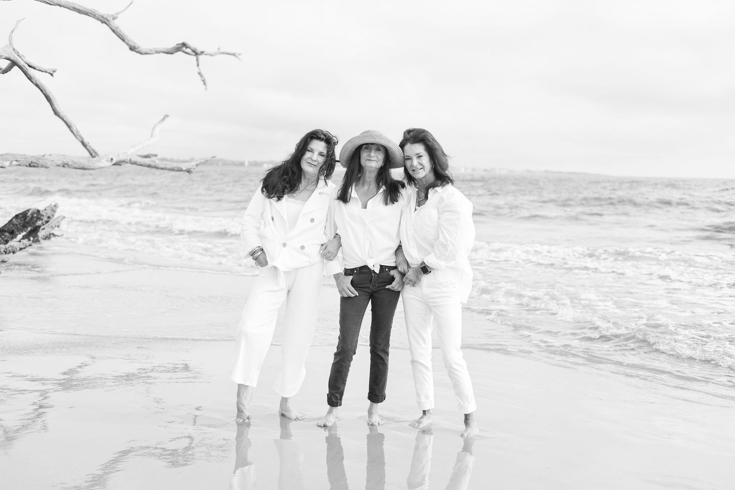 A group of people in white clothing walking together on a sandy beach at sunset.
