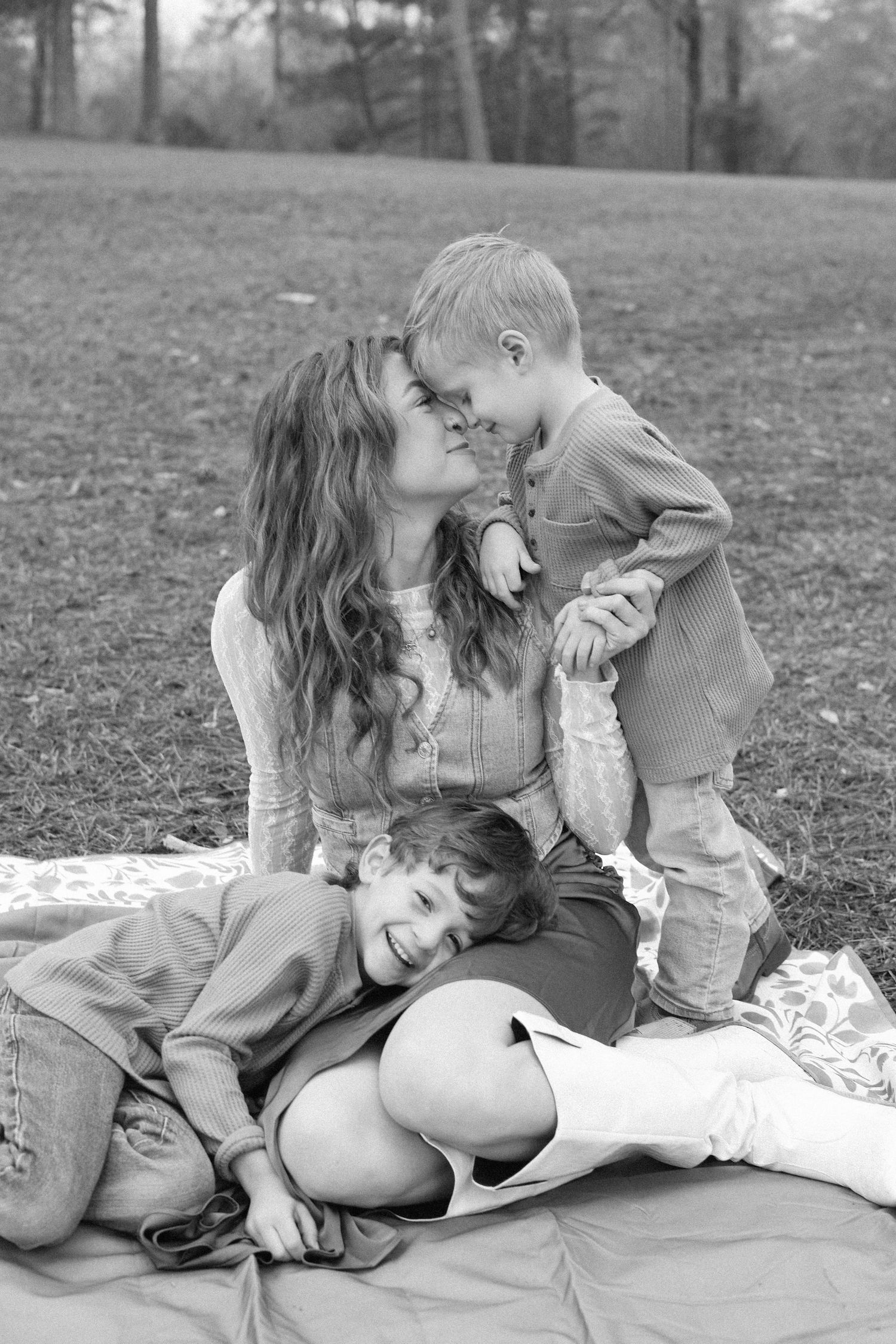 A tender black and white photo series showing a couple sharing intimate moments while sitting on a blanket outdoors.