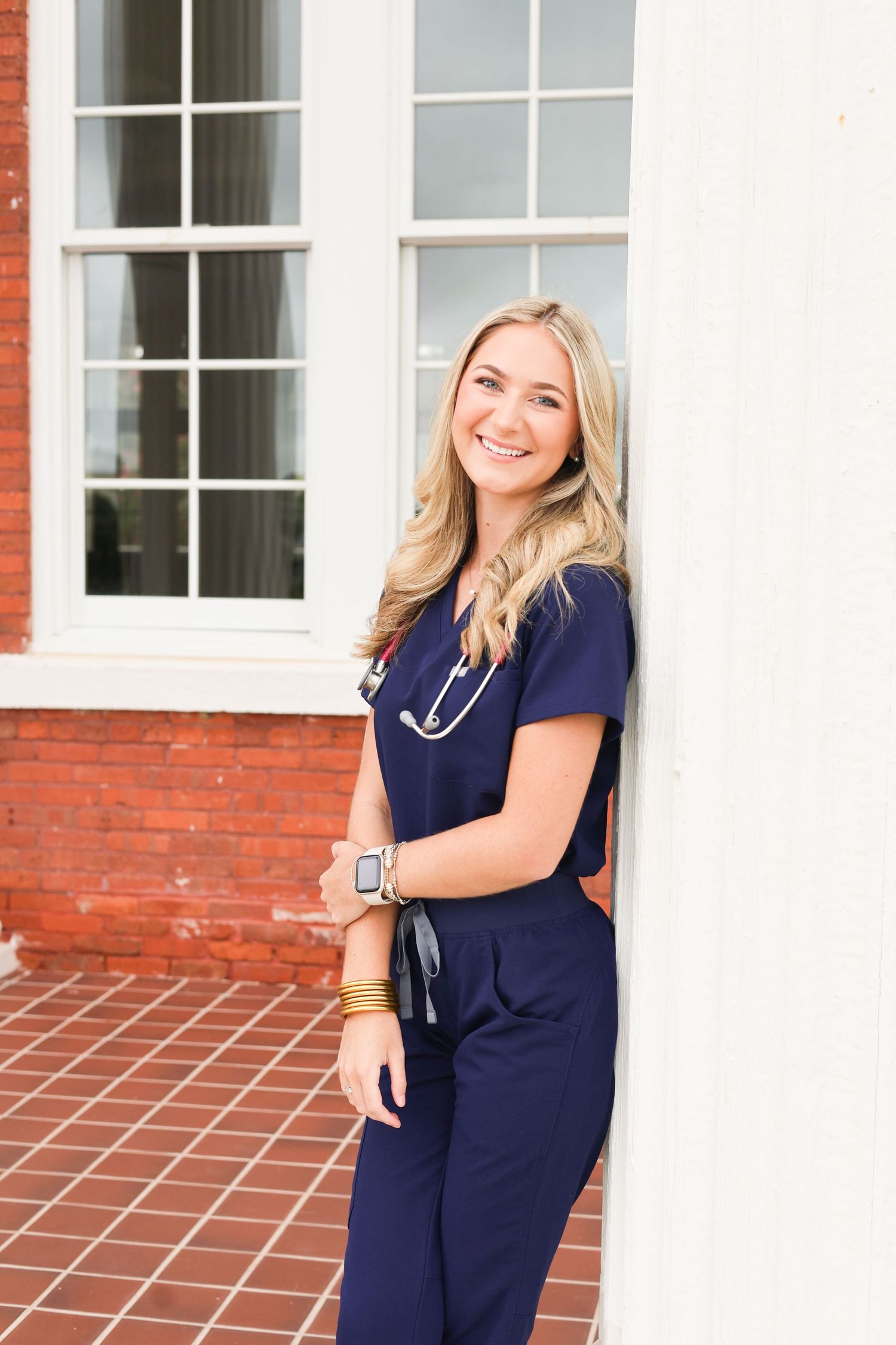 Healthcare professional in navy scrubs poses confidently outside a medical building.