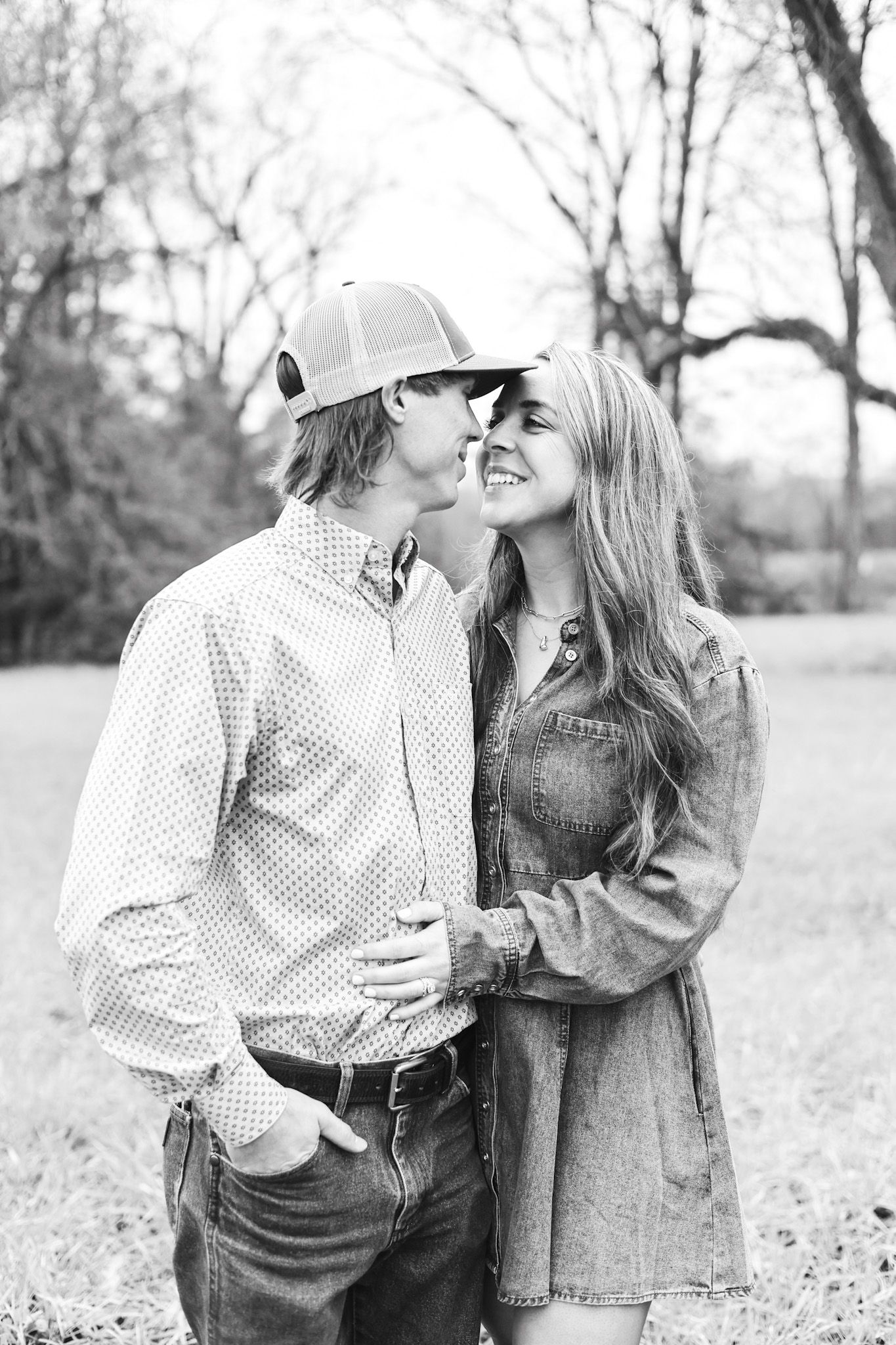 A casual couple shares a tender moment outdoors in black and white photography.